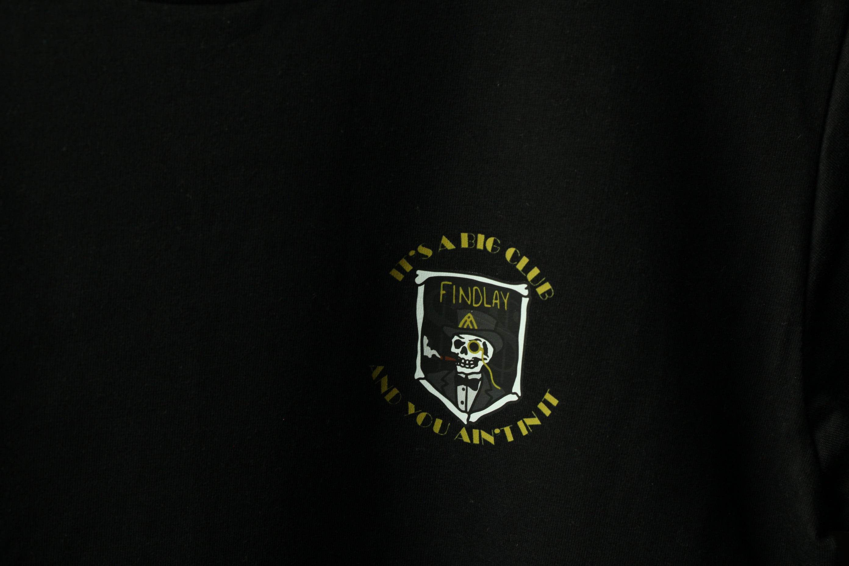 The image is a black t-shirt with a white and yellow graphic design on it.