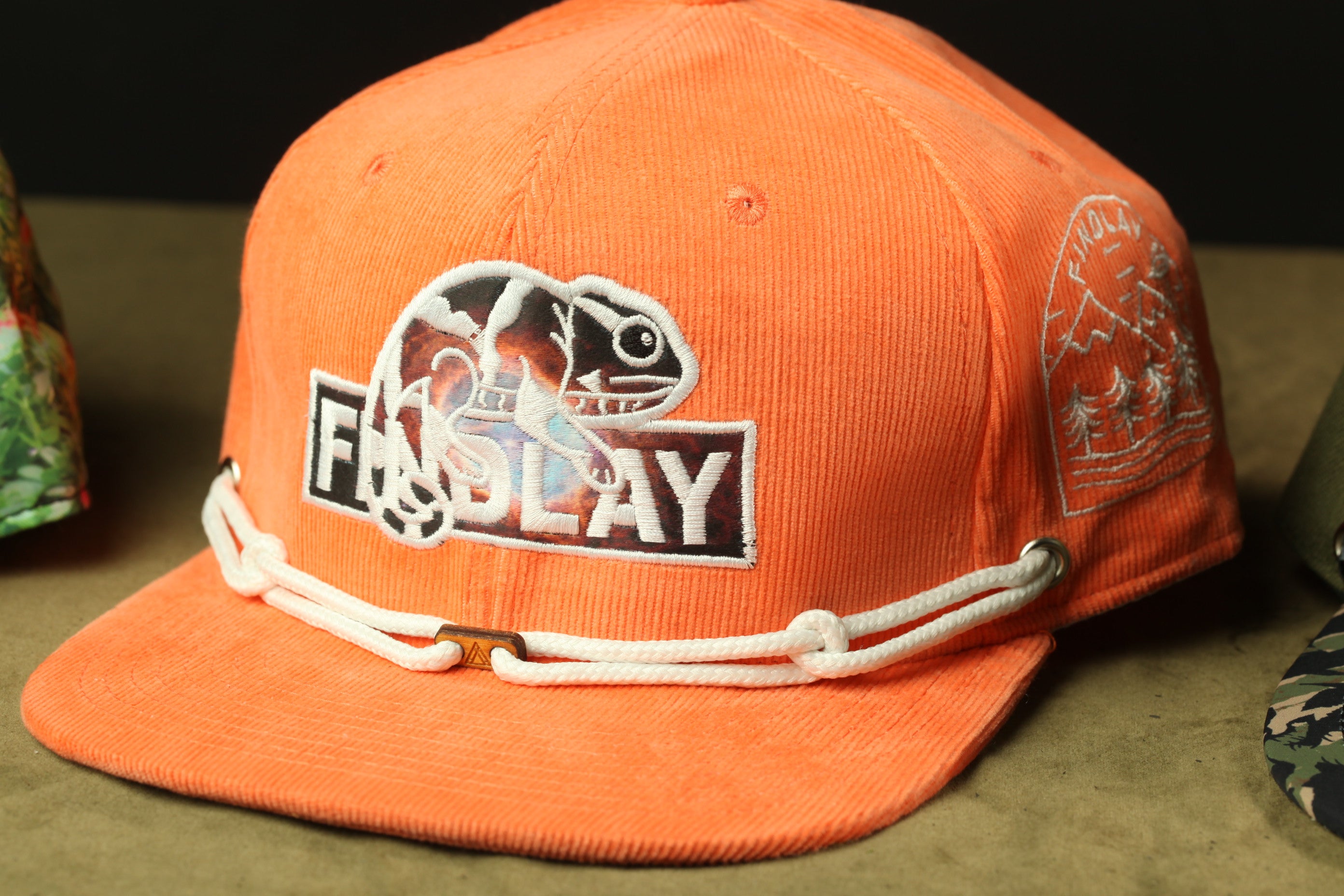 An orange baseball cap with a white and black logo on it.