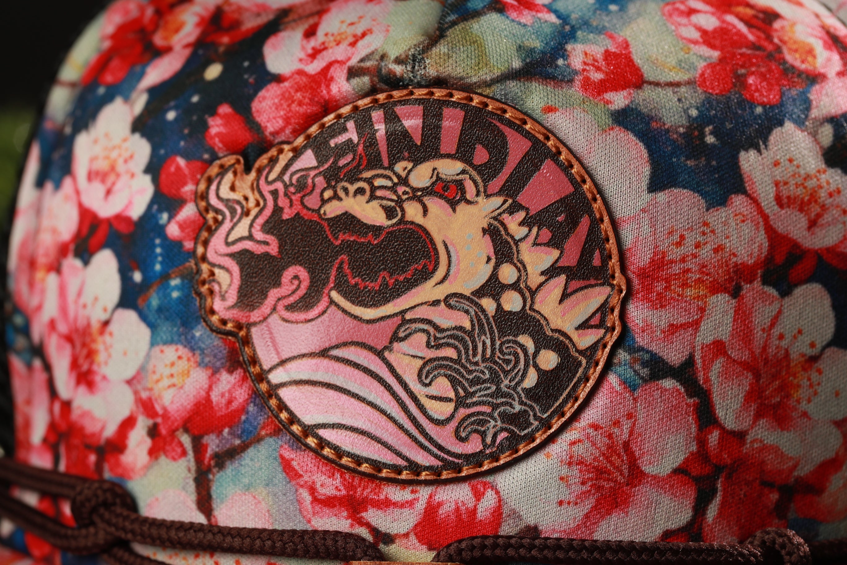 A close-up of a colorful, floral-patterned fabric with a circular patch featuring a stylized dragon or mythical creature design.