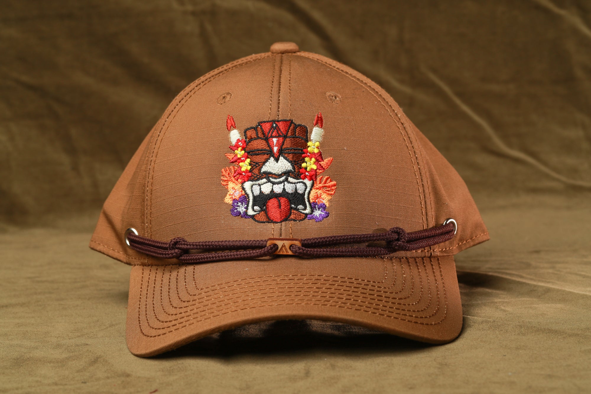 A brown baseball cap with a colorful, embroidered design on the front.