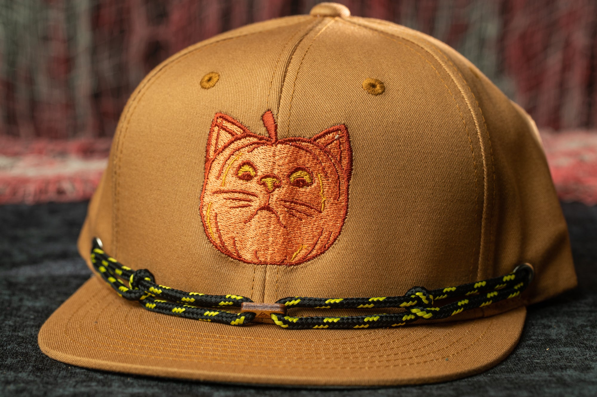 A brown baseball cap with a cat embroidered on the front.