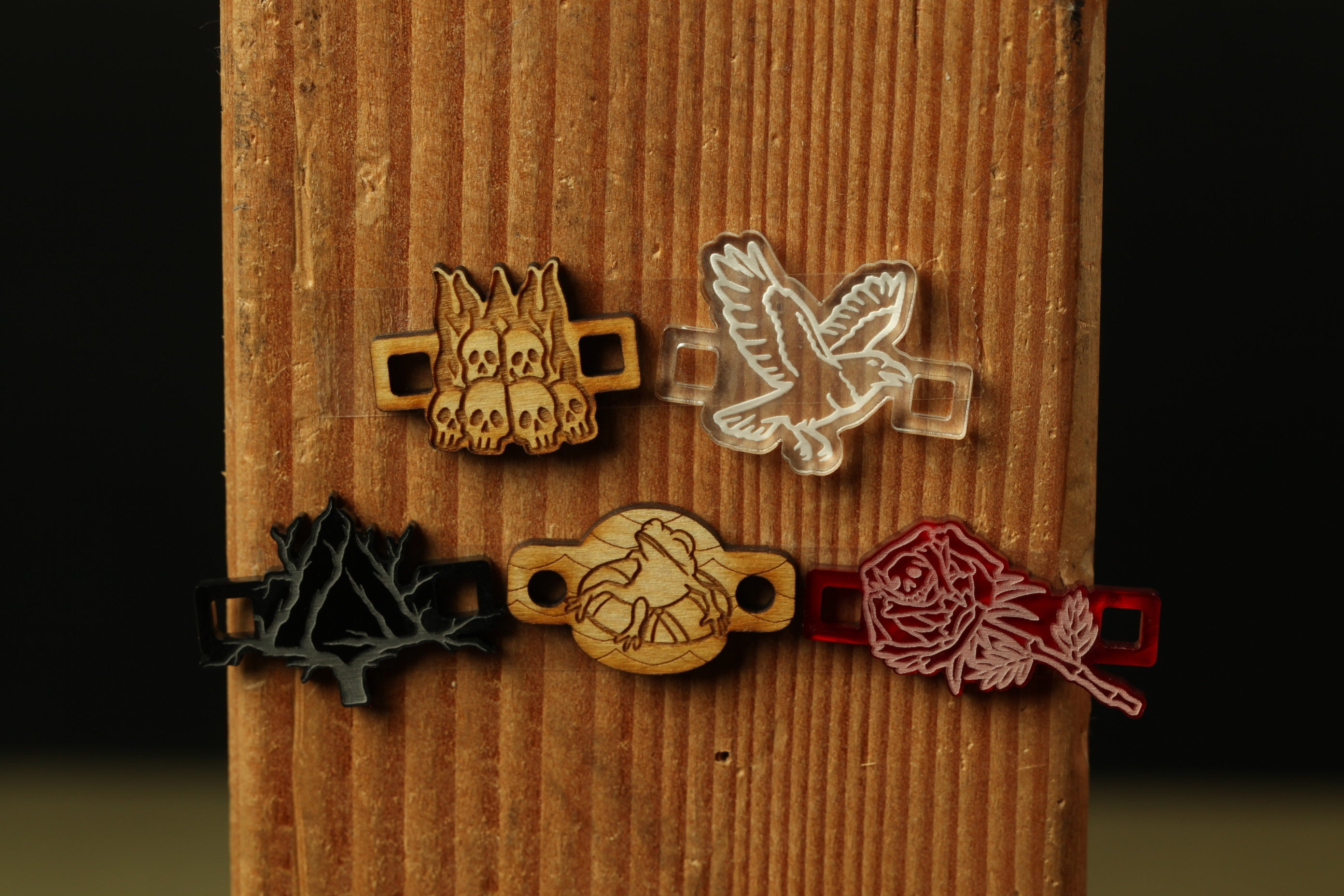 a wooden surface with various engraved or printed objects, including a bird, a skull, a rose, and a tree.