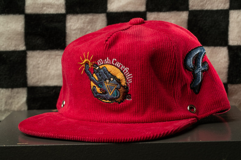A red baseball cap with a sun and palm tree design, featuring a small embroidered logo on the front.
