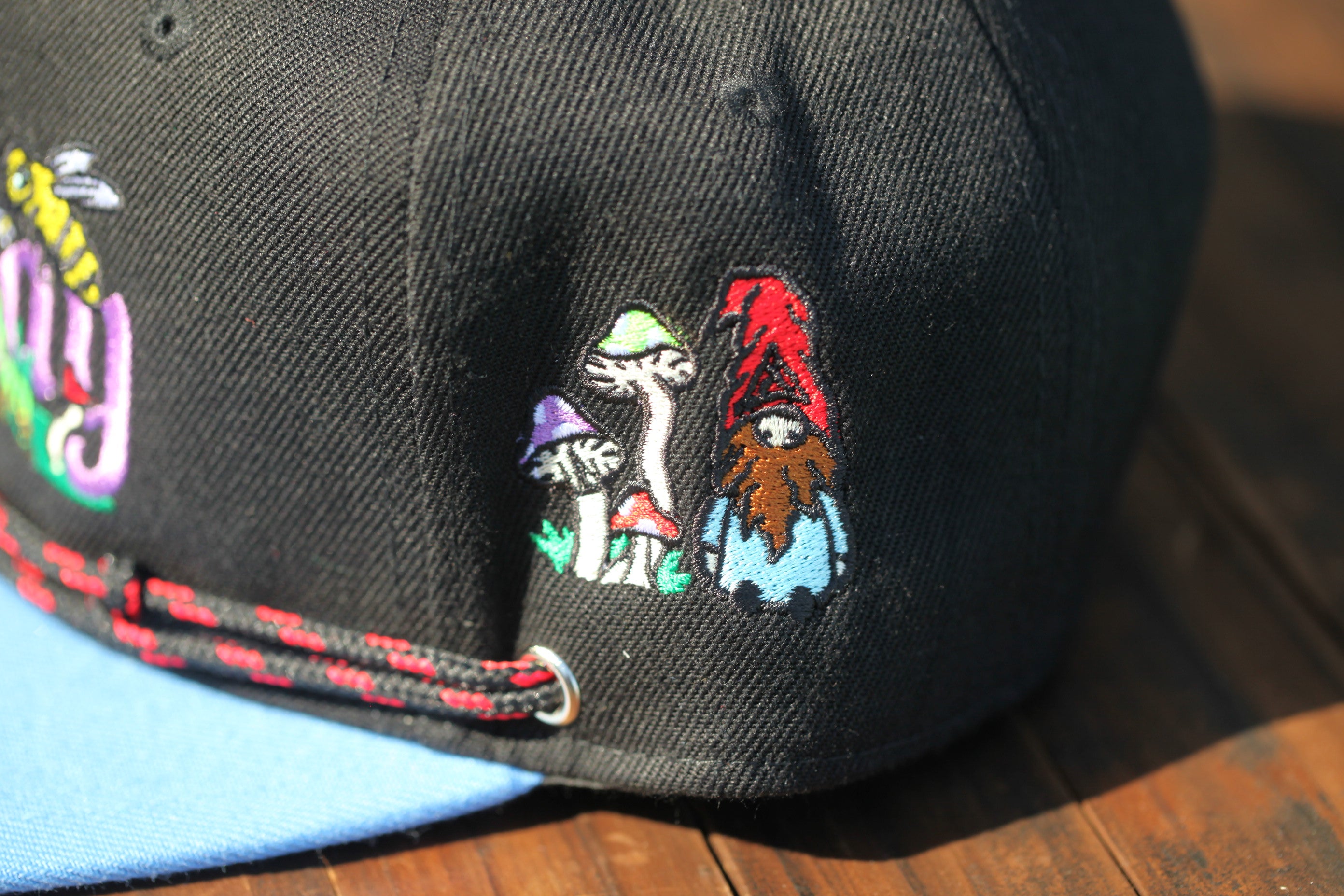 a close-up view of a black baseball cap with colorful embroidered designs on the front.