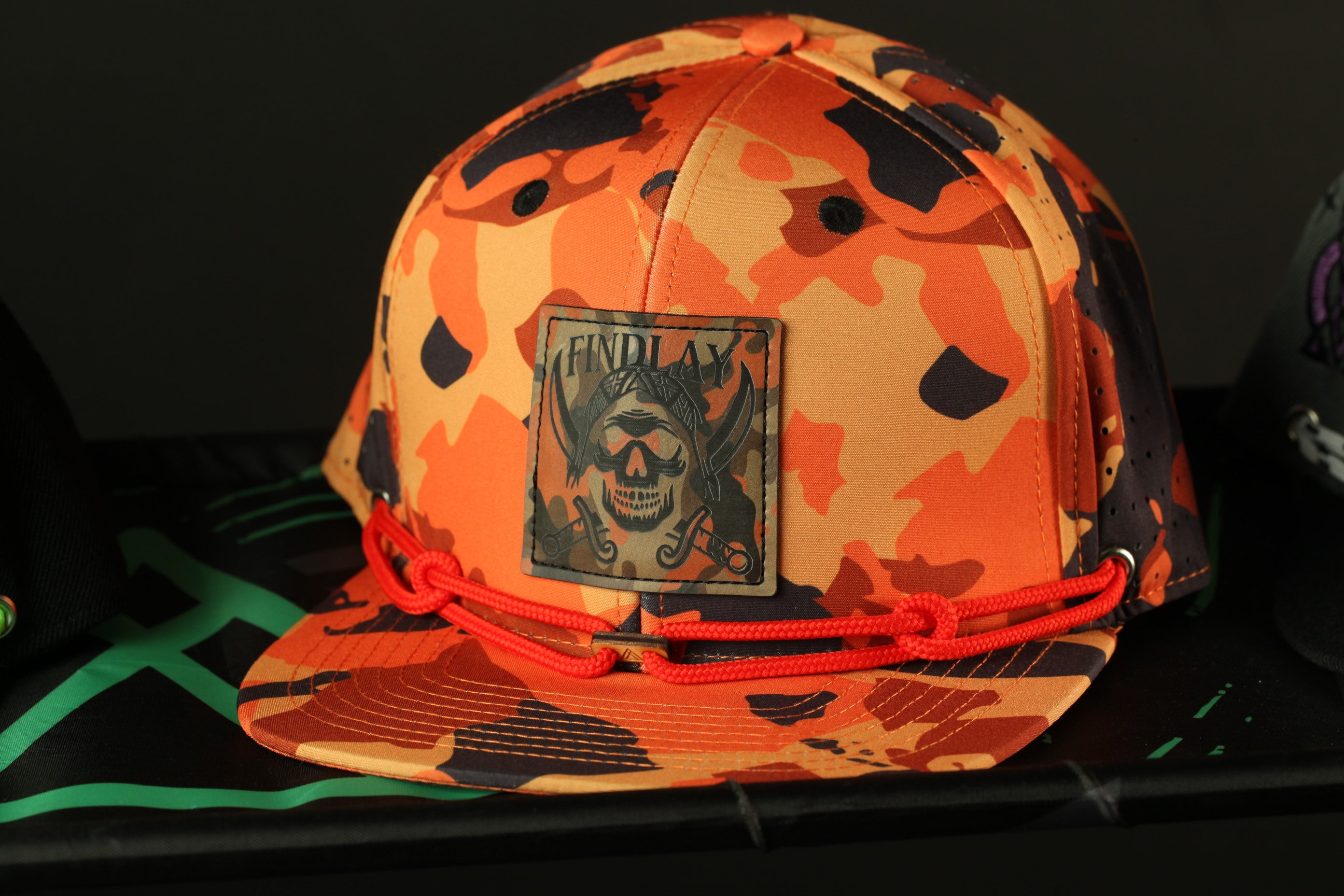 A camouflage baseball cap with a skull patch and red string.