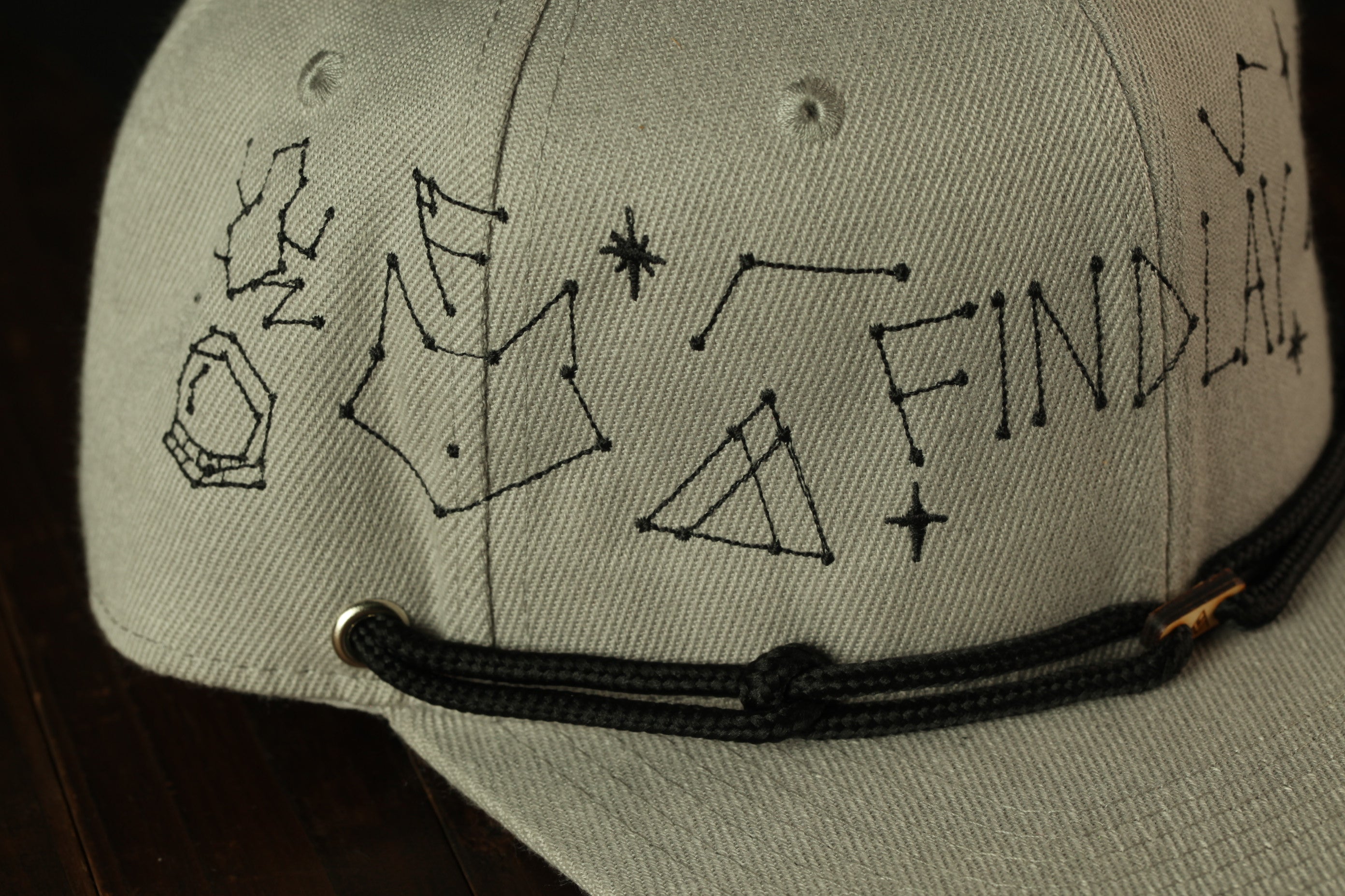 a gray baseball cap with black text and drawings on it.