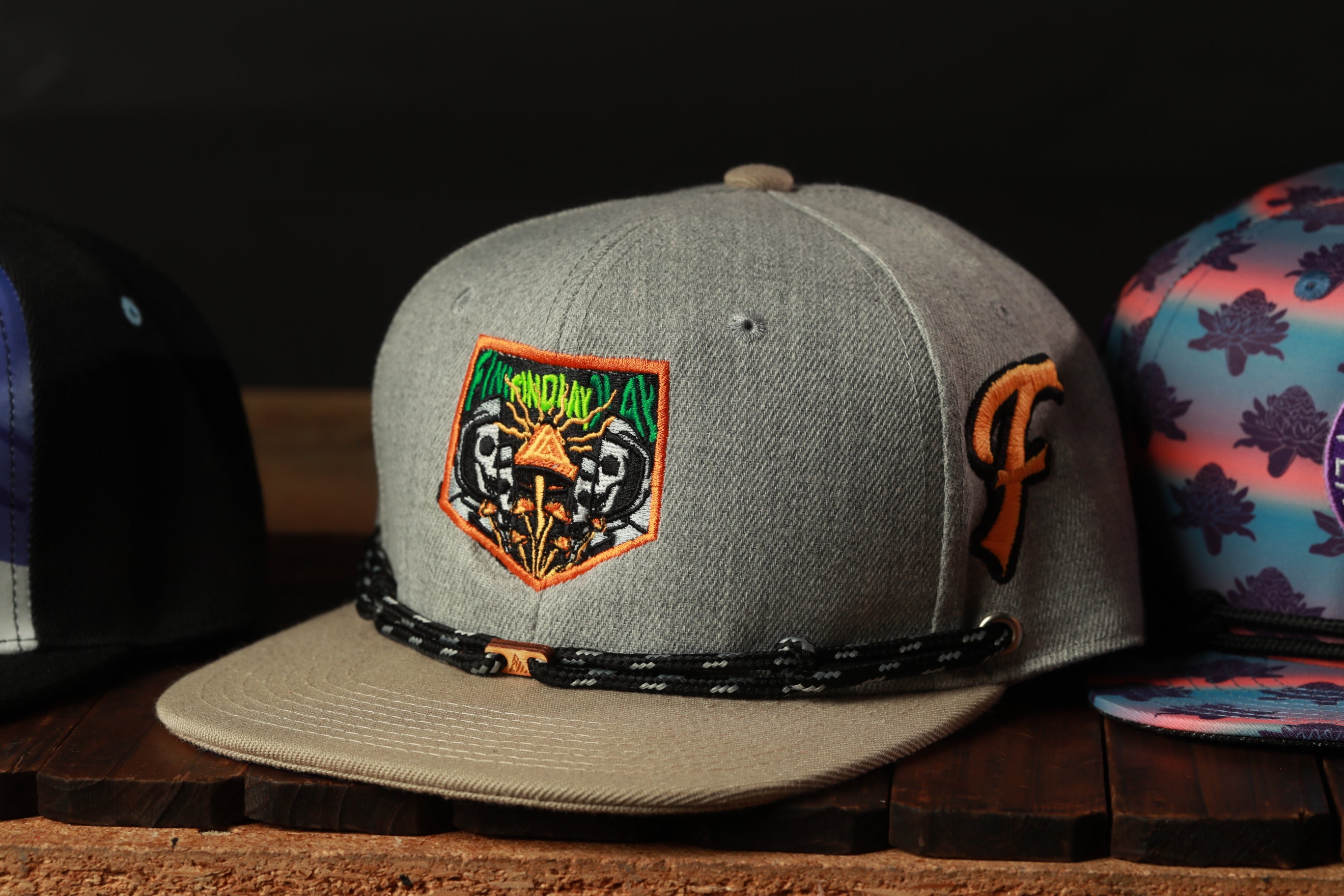 A gray baseball cap with a unique patch on the front, sitting on a wooden surface.
