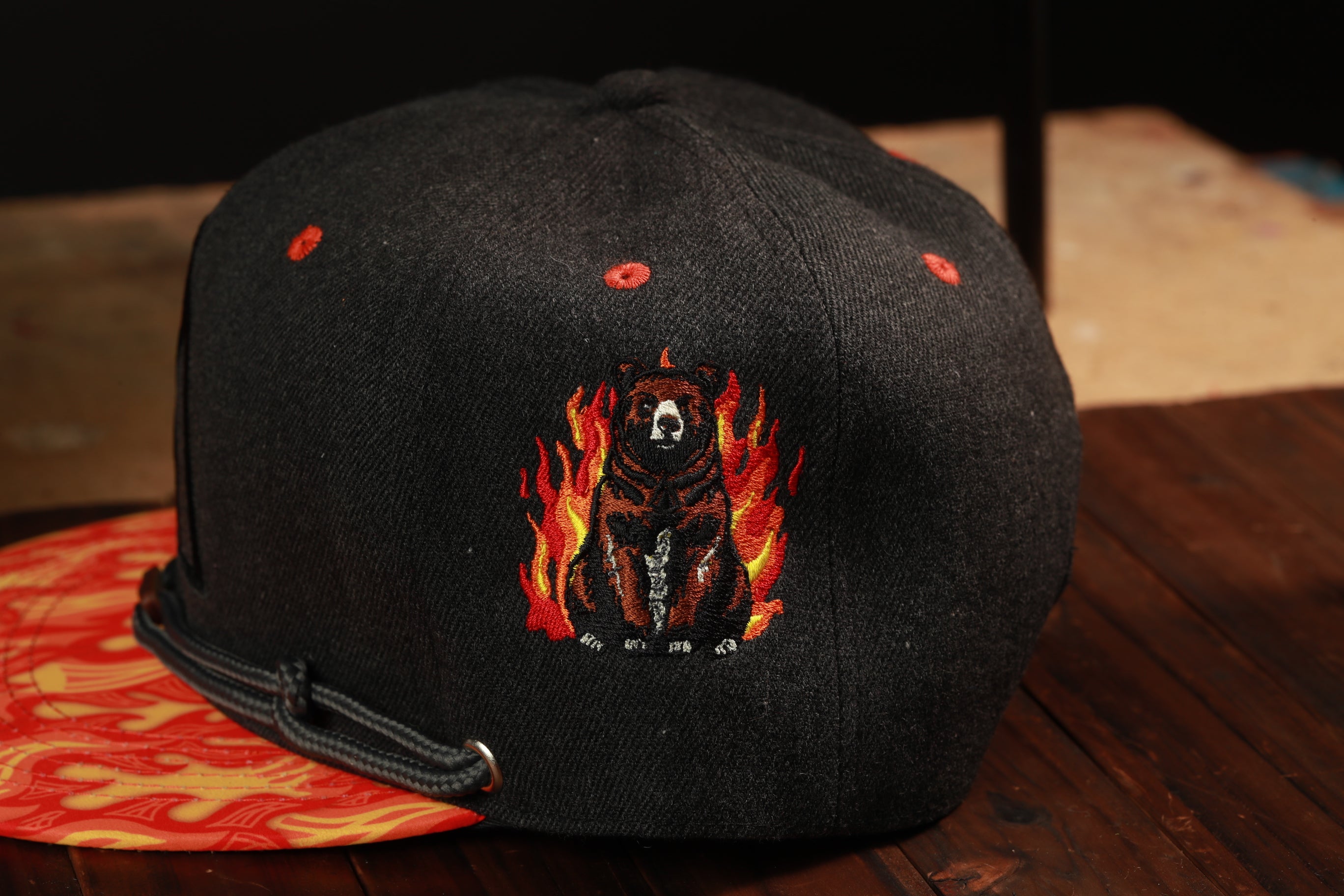 A black baseball cap with a graphic of a bear surrounded by flames on the front.