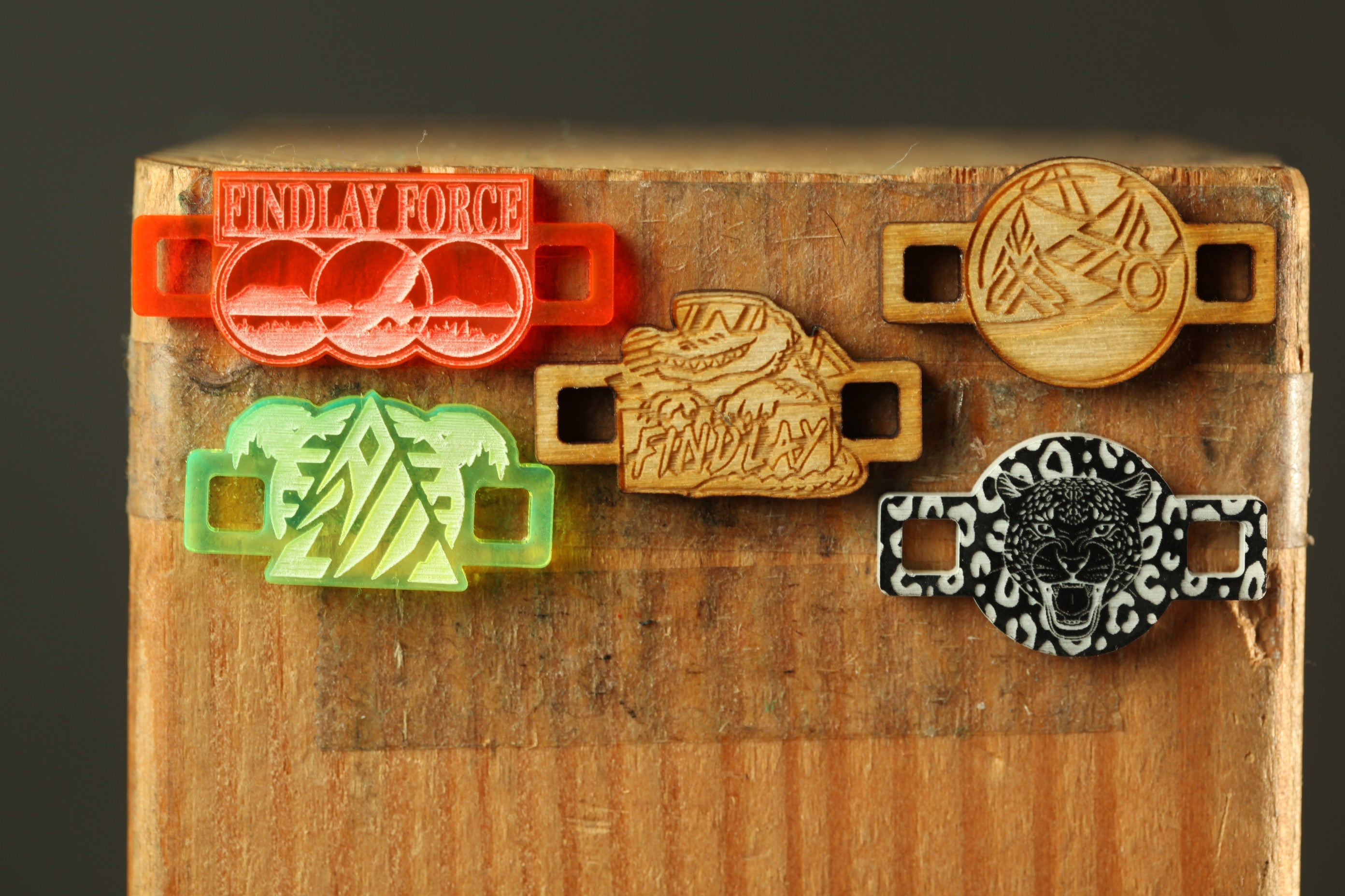 a collection of five wooden shoe lace holders, each with a unique design, displayed on a wooden surface.