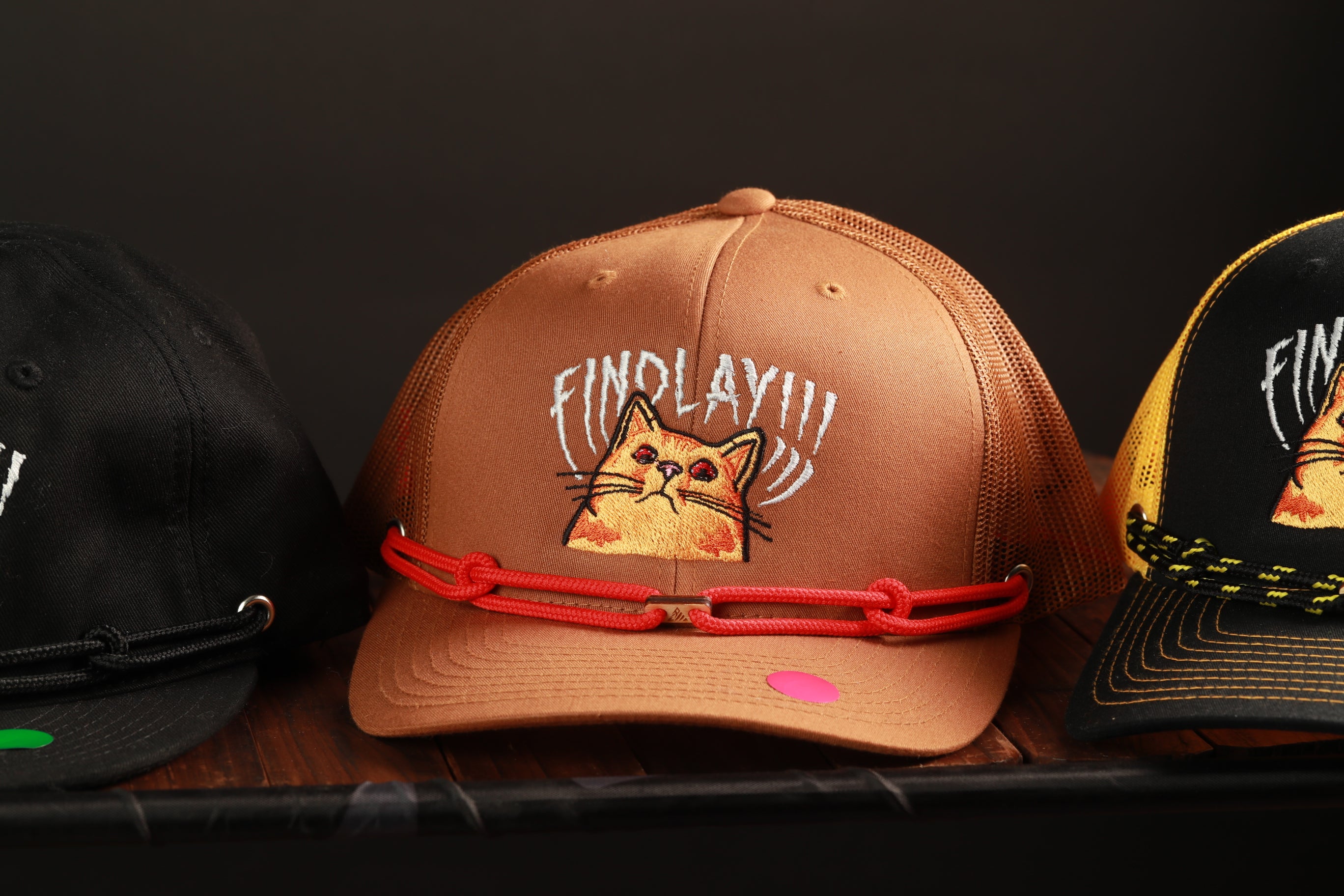 Three baseball caps with different designs and colors are displayed on a shelf.
