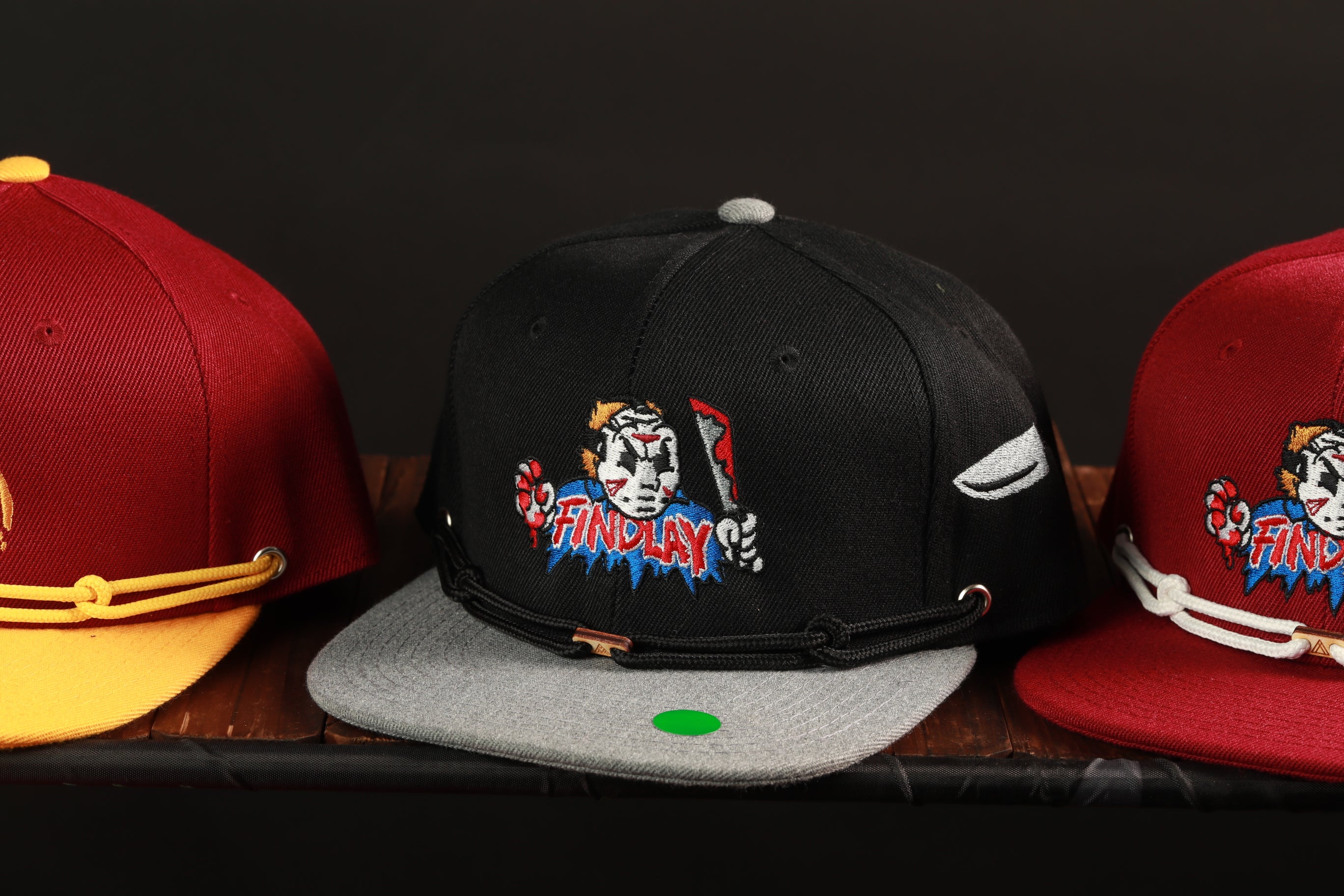 Three baseball caps with different colors and designs are displayed on a shelf.