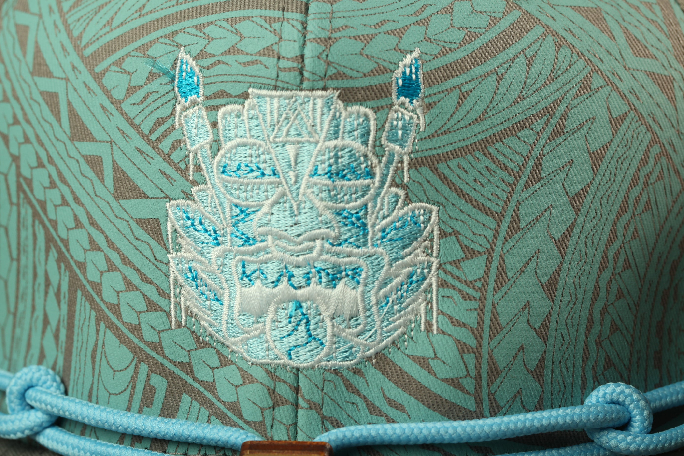 a close-up view of a hat with a blue and white embroidered design on the front.