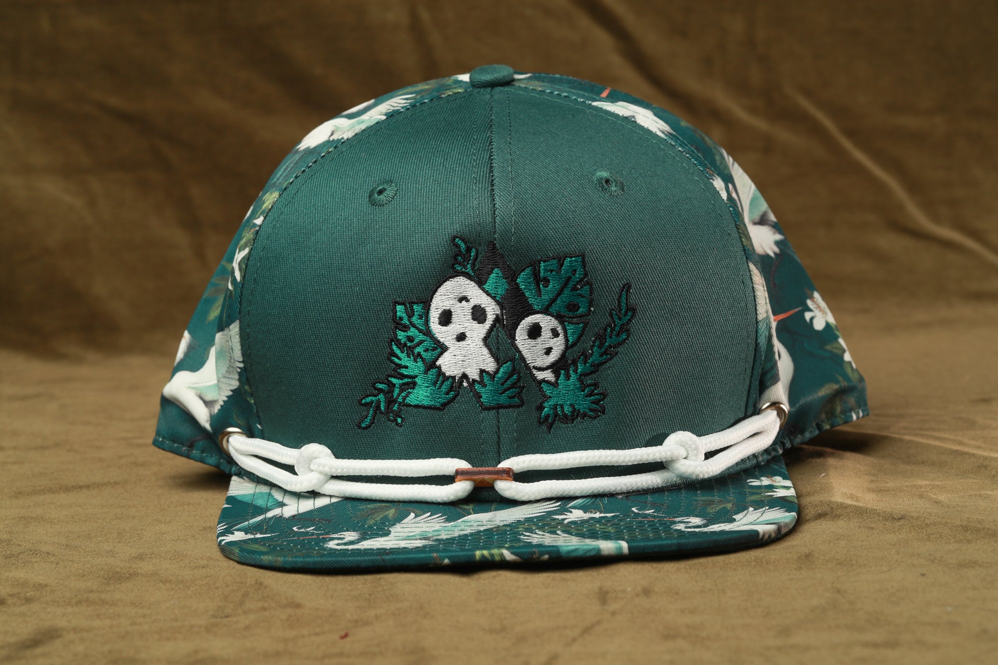 A green baseball cap with a floral pattern and a skull design on the front.