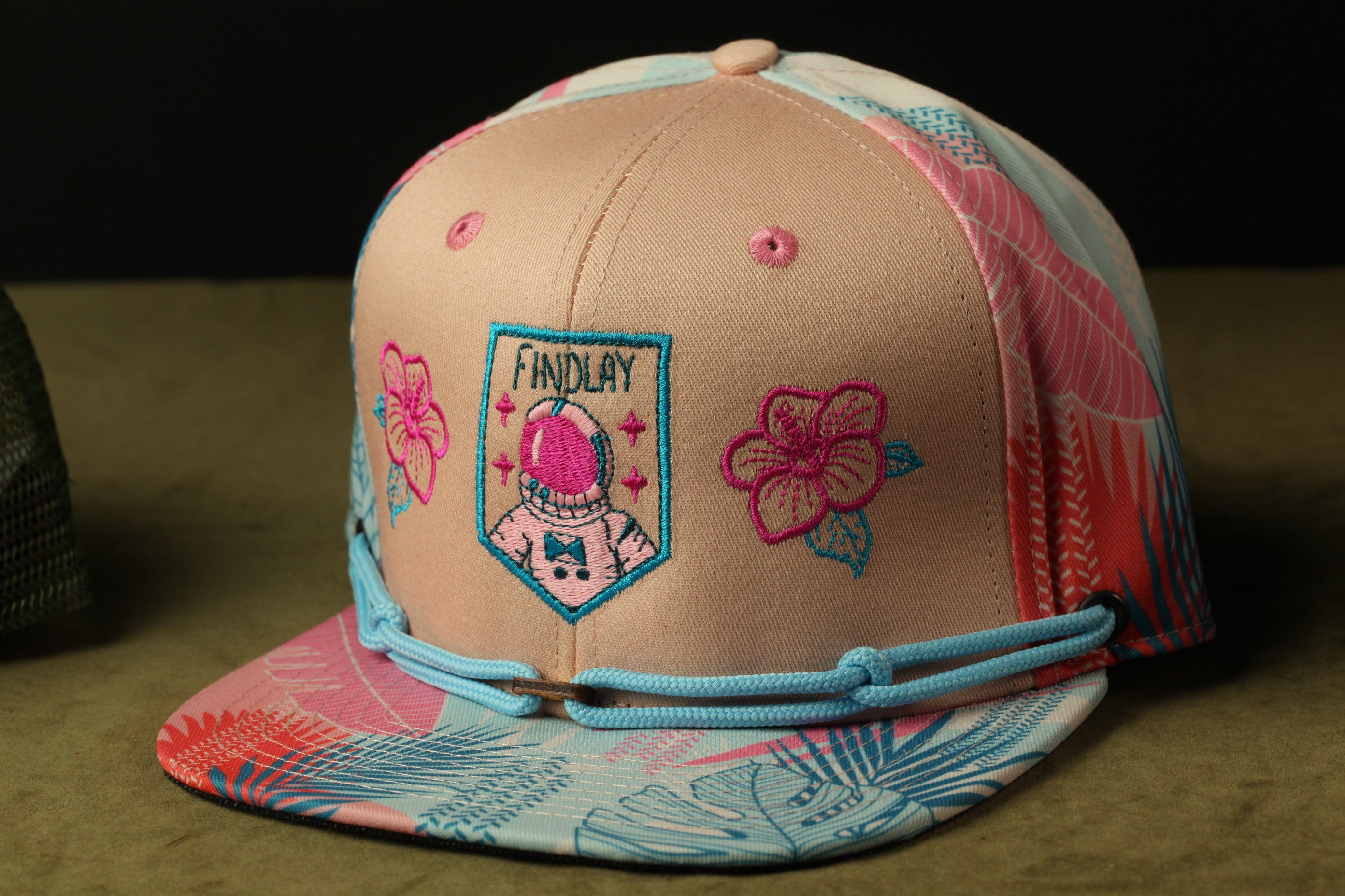 A colorful baseball cap with a floral pattern and a small embroidered patch on the front.