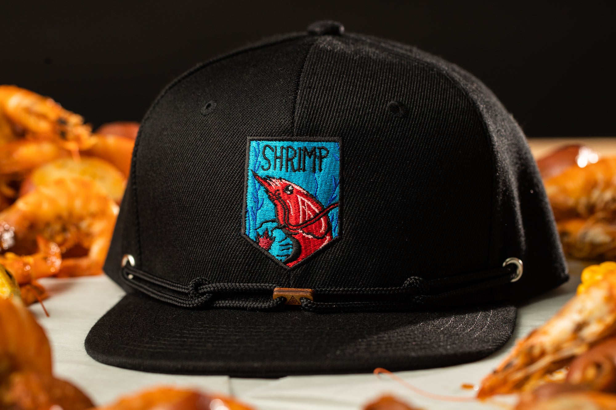 a black hat with a red shrimp patch on it