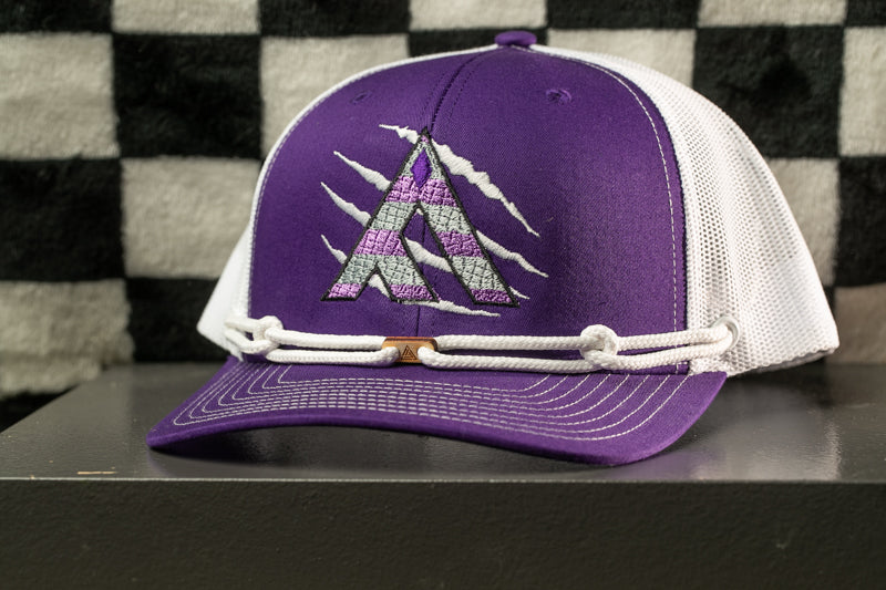 A purple baseball cap with a white mesh panel and a purple logo on the front, sitting on a gray surface against a black and white checkered background.