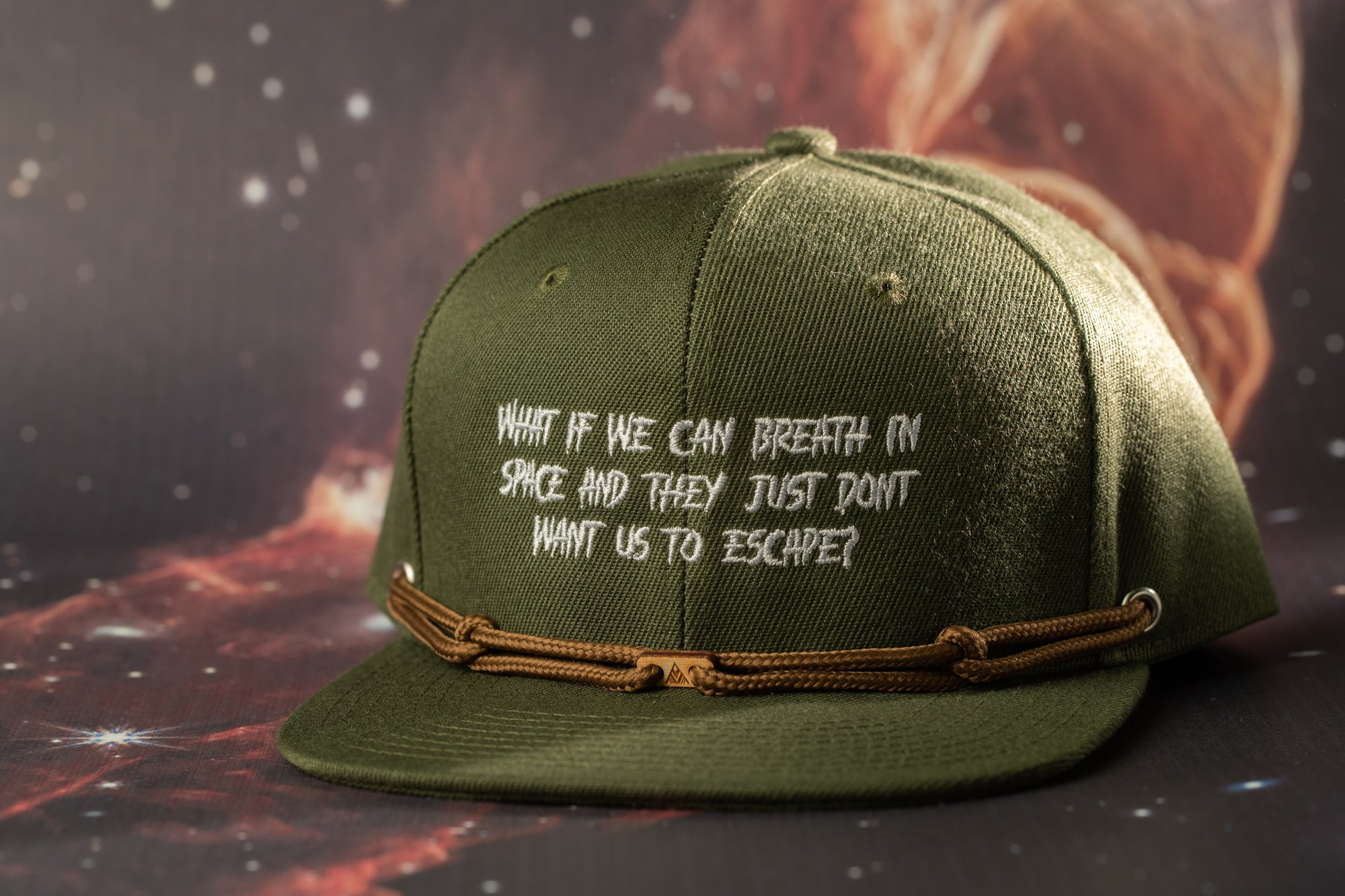 A green baseball cap with white text on it, placed on a dark background with a red and orange gradient.