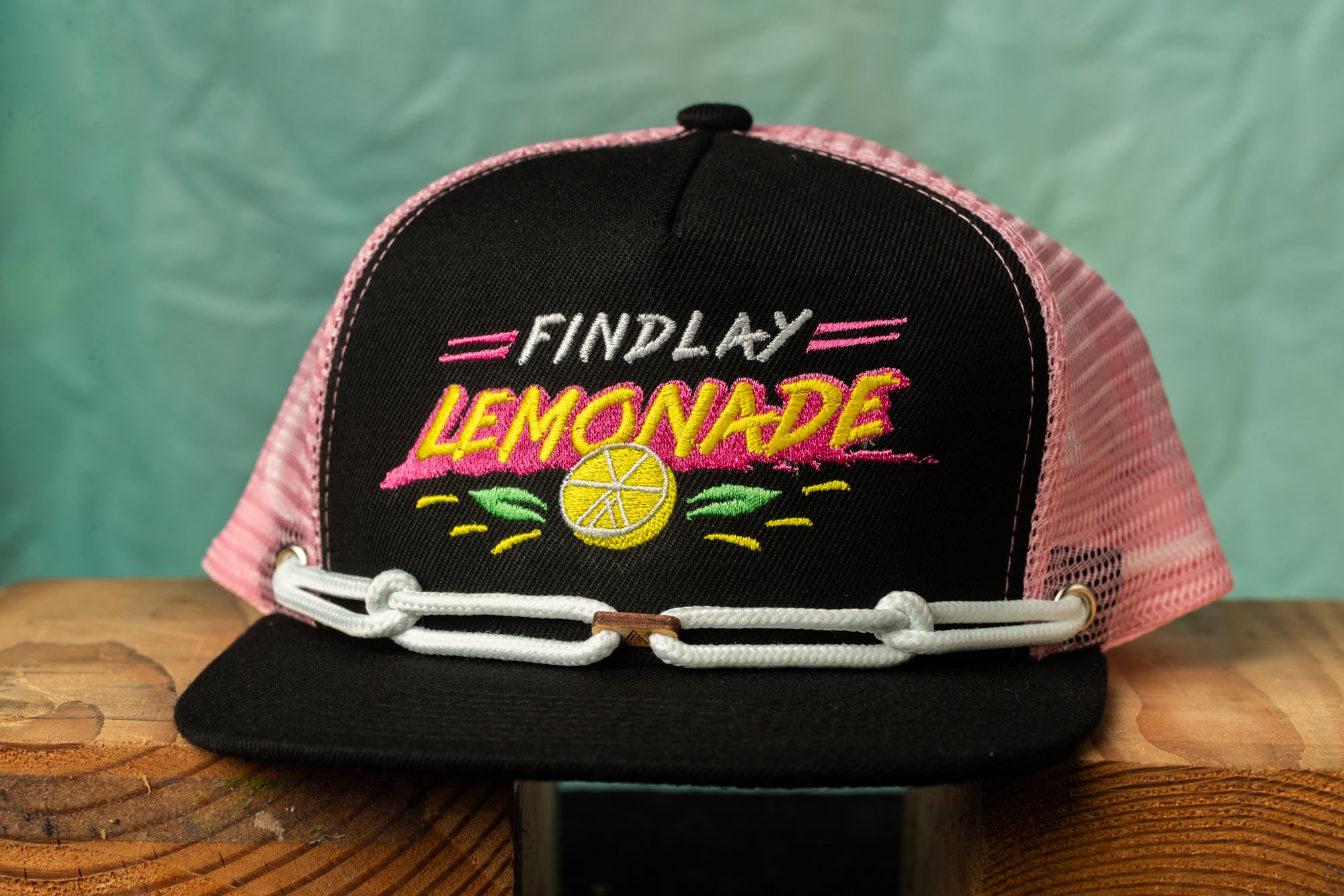A black baseball cap with a pink mesh panel and the text "FIND LEMONADE" printed on it.