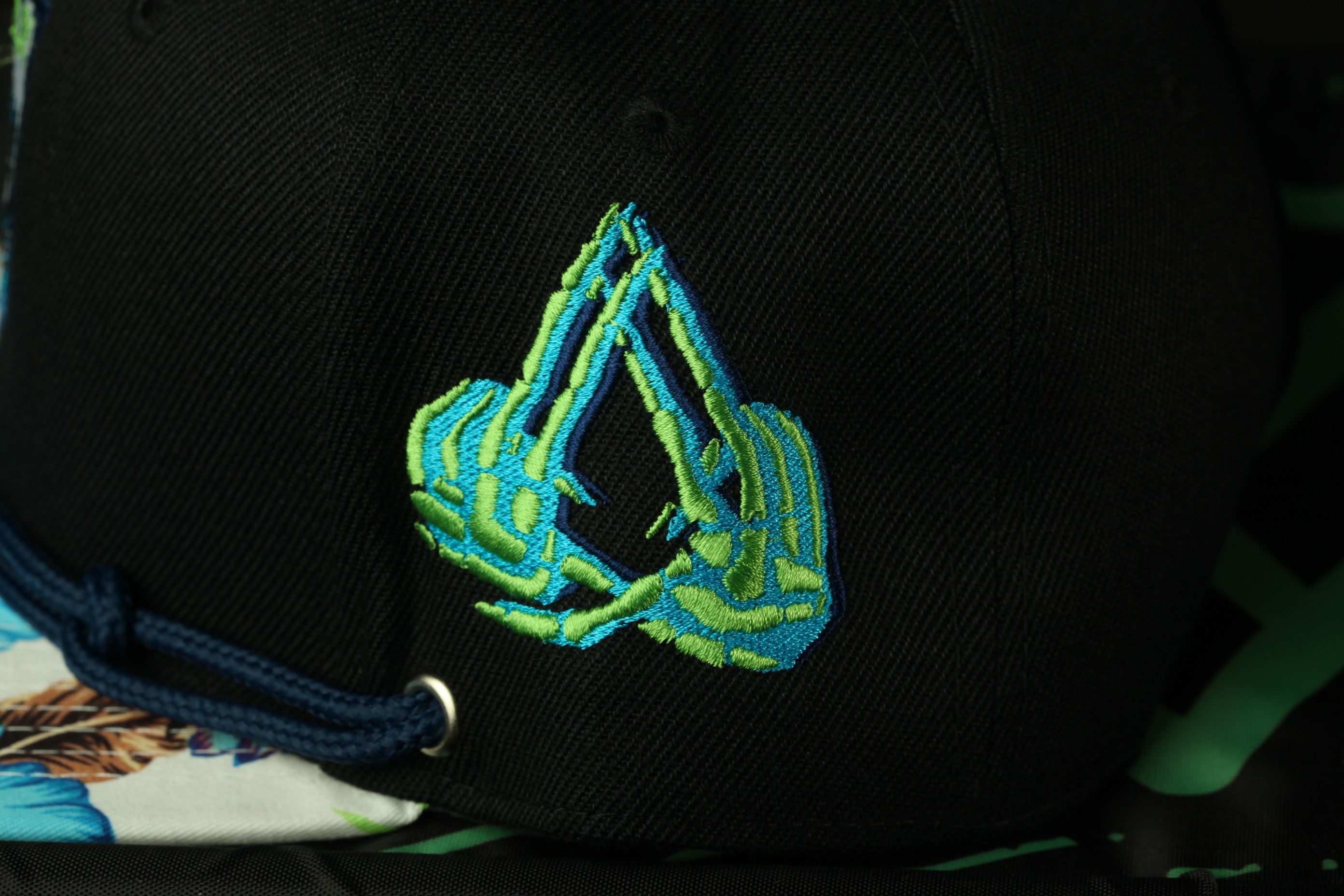 a close-up view of a black baseball cap with a unique embroidered design on the front.