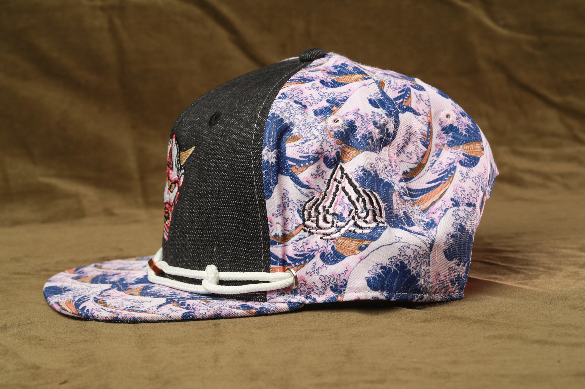 A colorful baseball cap with a black and white wave pattern and a black brim, featuring a small embroidered logo on the side.