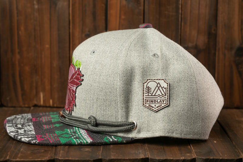 A gray baseball cap with a colorful, patterned fabric and a small, embossed logo on the front.