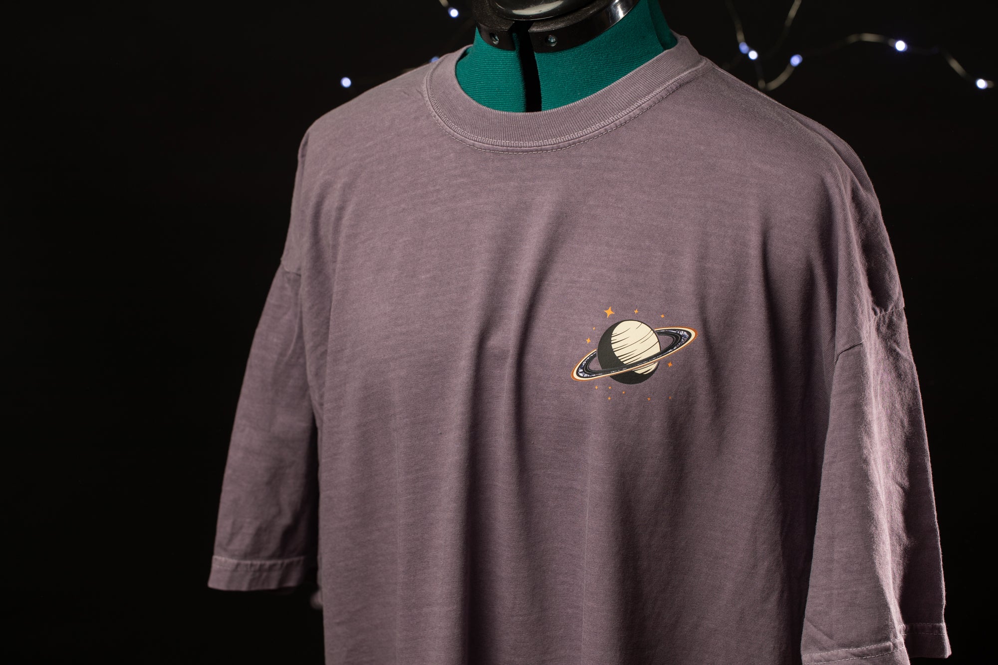A mannequin wearing a gray t-shirt with a graphic of a planet and stars on the front.