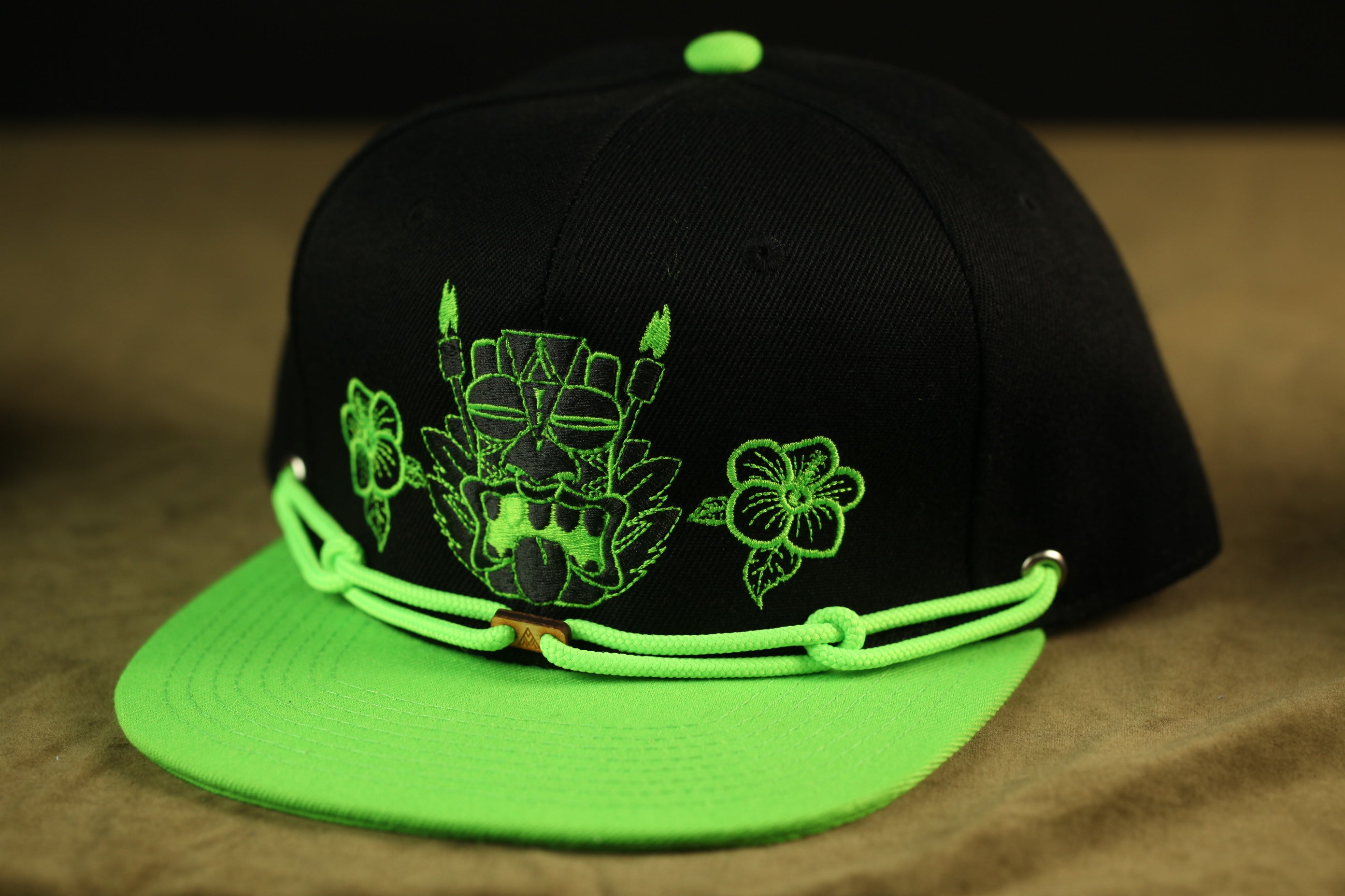 A black baseball cap with a green brim and a graphic design on the front.
