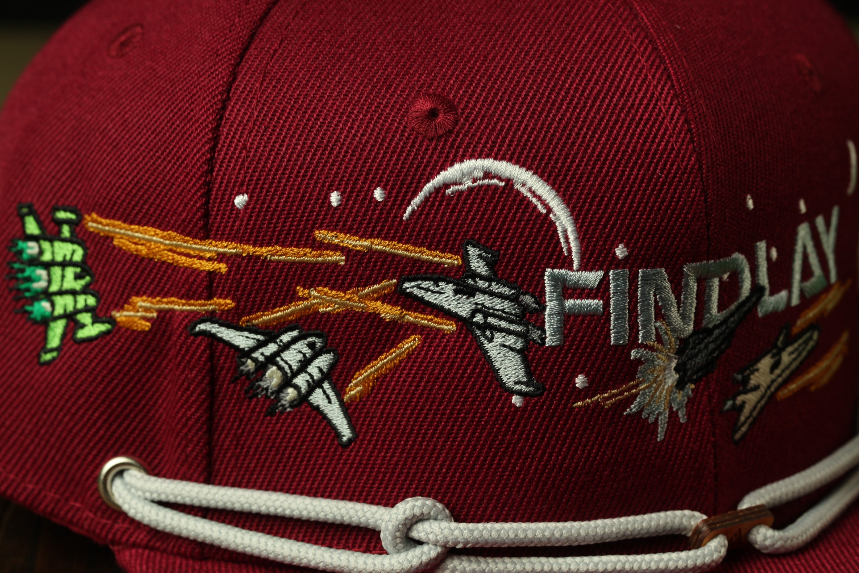 a close-up view of a red baseball cap with various embroidered designs and text.