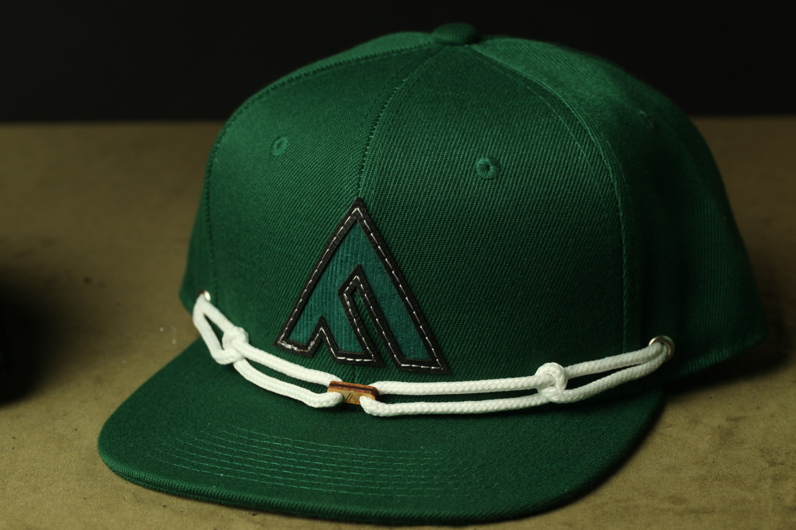 A green baseball cap with a white rope around the brim.