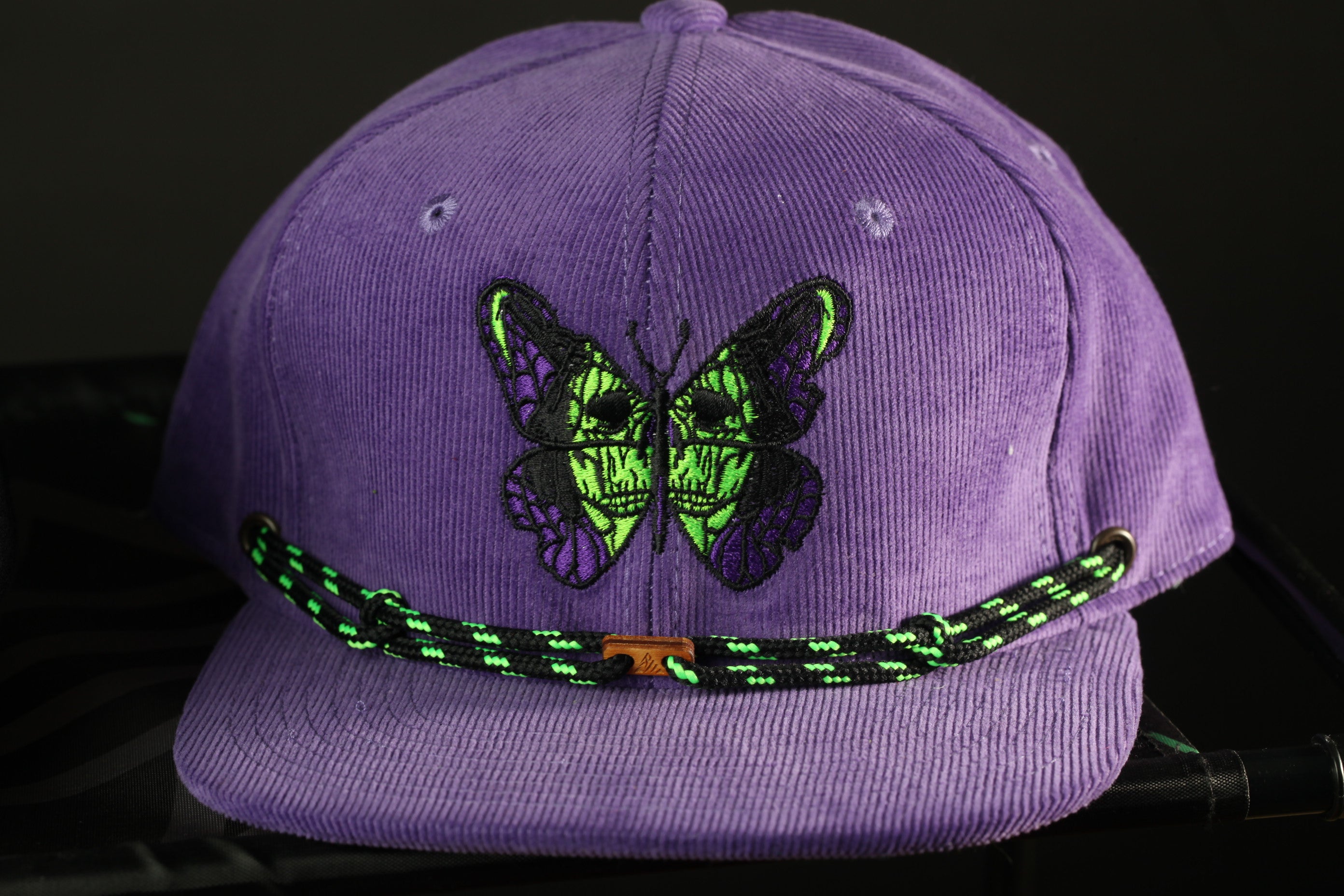 A purple baseball cap with a green and black butterfly design on the front.
