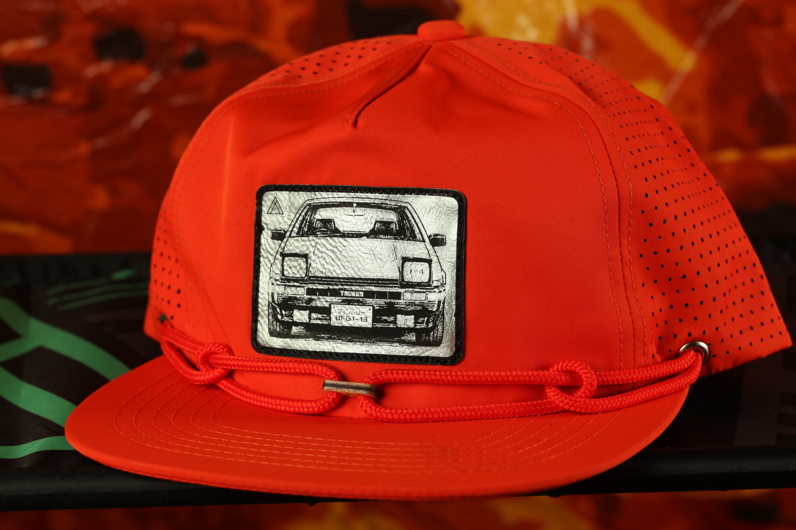 A bright red baseball cap with a black and white graphic of a car on the front.