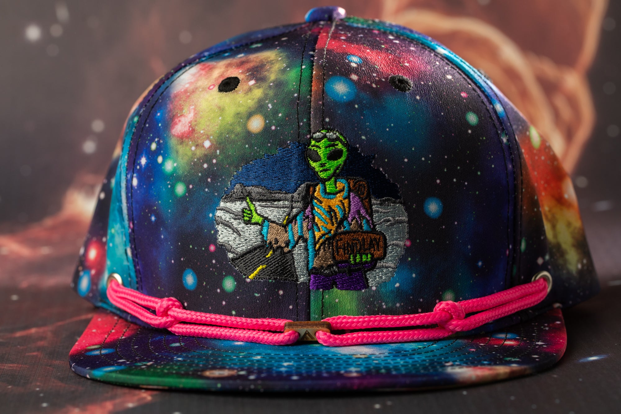 A colorful, space-themed baseball cap with a unique alien design on the front.