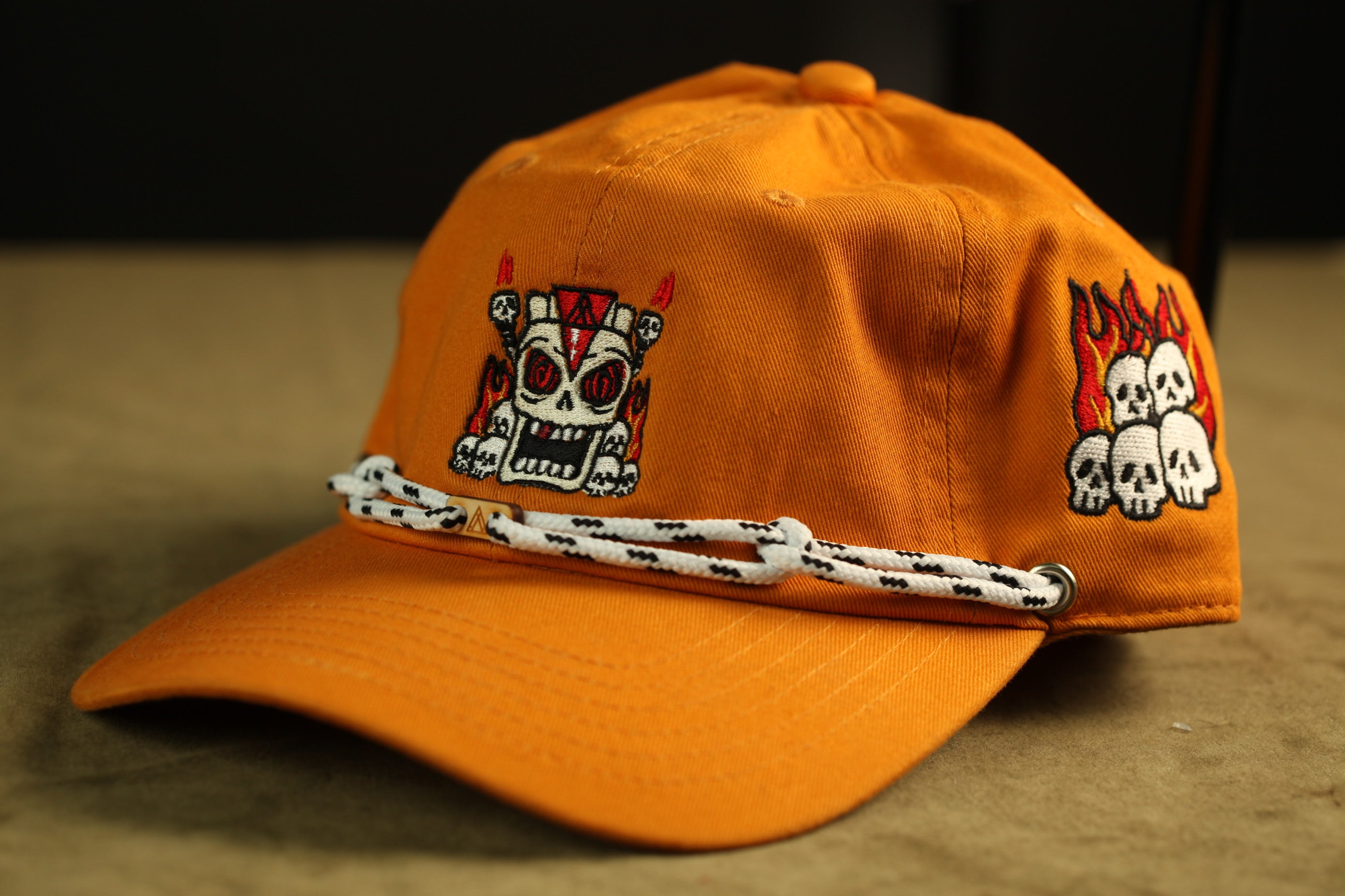 An orange baseball cap with a skull design on it.