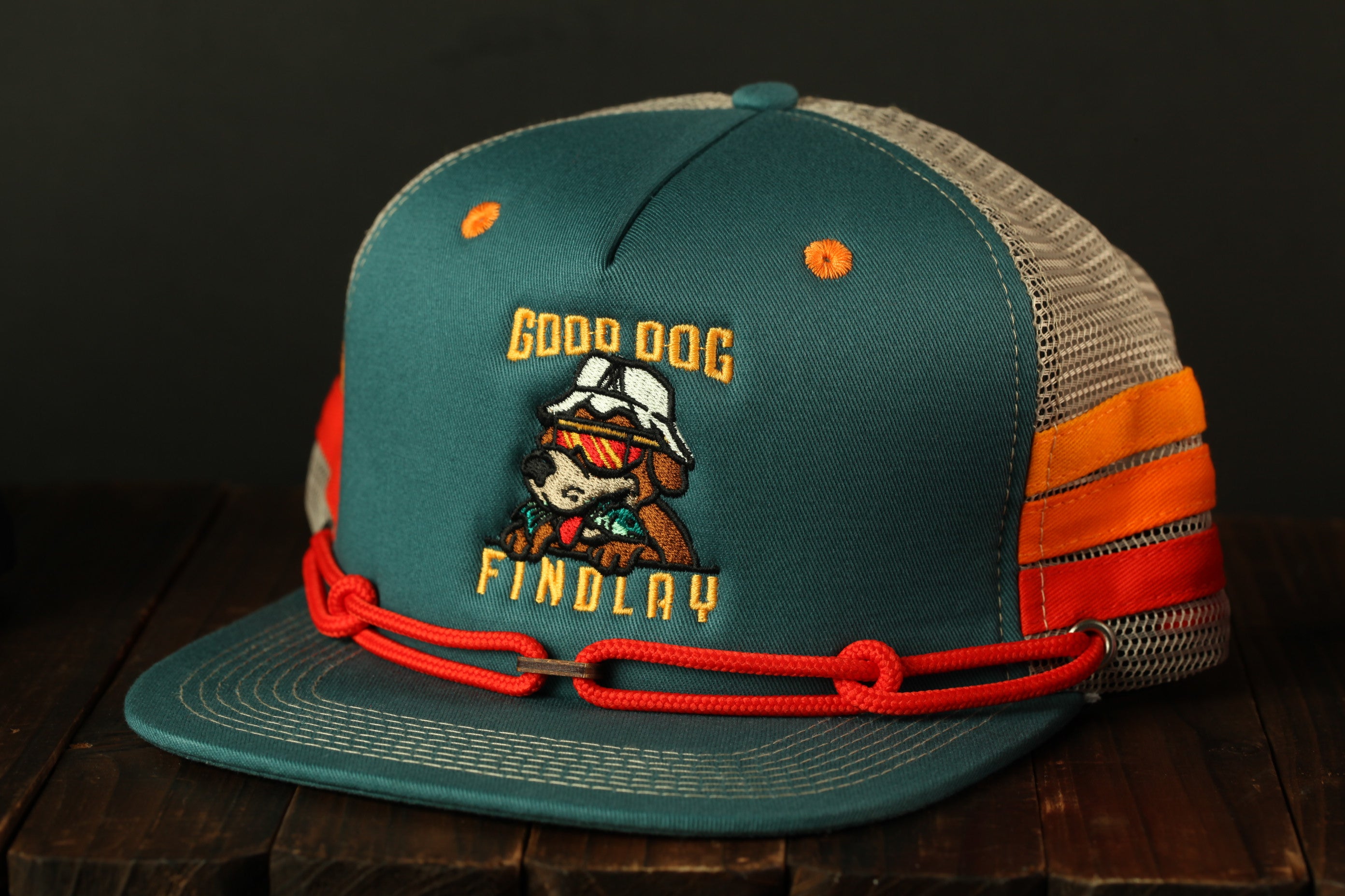 A green baseball cap with a cartoon dog and the text "GOOD DOG FINDOLAY" printed on it.