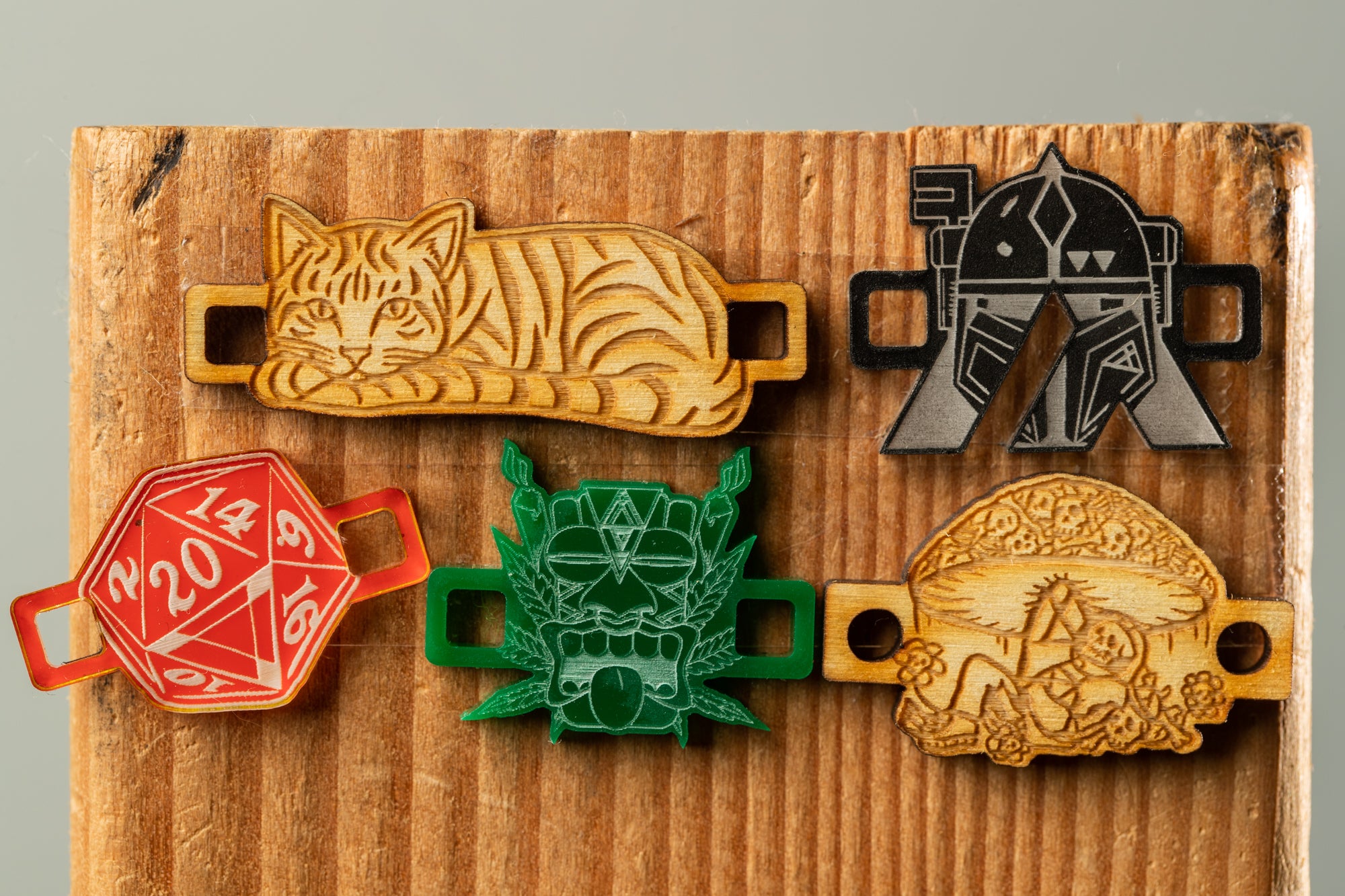 a collection of five distinct badges or charms, each with unique designs and patterns, displayed on a wooden surface.