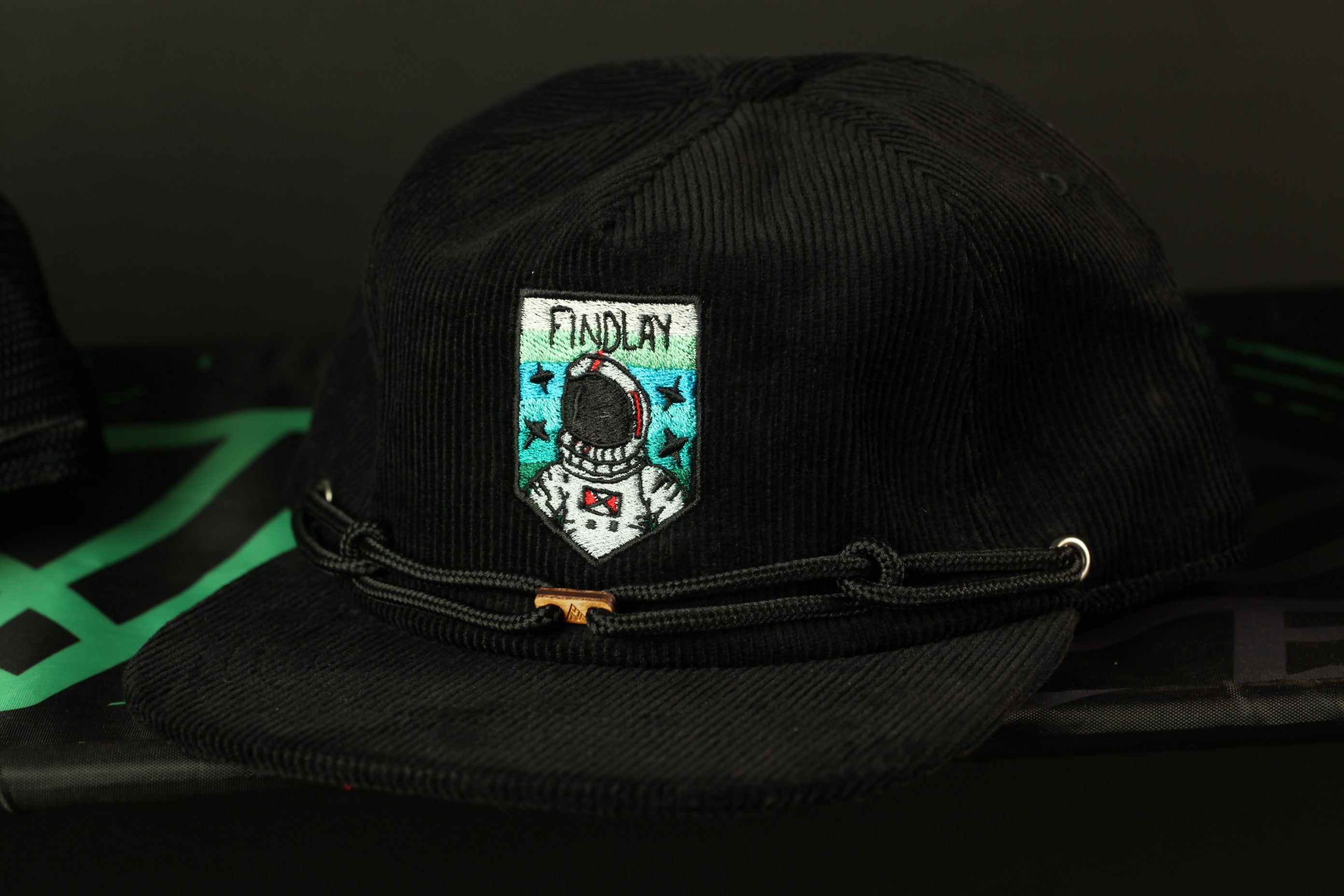 A black baseball cap with a white and blue patch featuring an astronaut and the word "FINDLAY" printed on it.