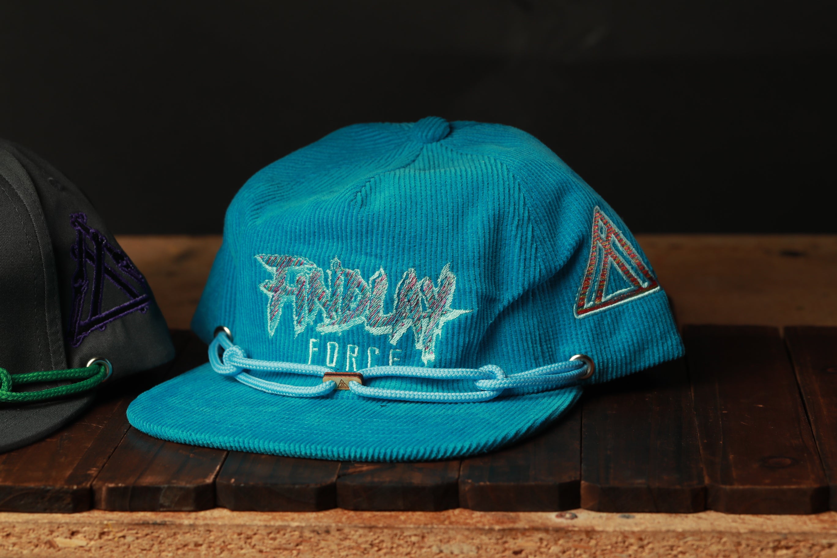 A blue baseball cap with the text "FRIDAY FORCE" printed on it, sitting on a wooden surface.