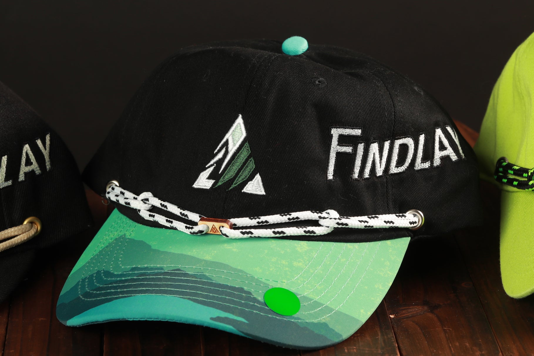A black baseball cap with the word "Findlay" printed on it, along with a green and blue patterned brim.