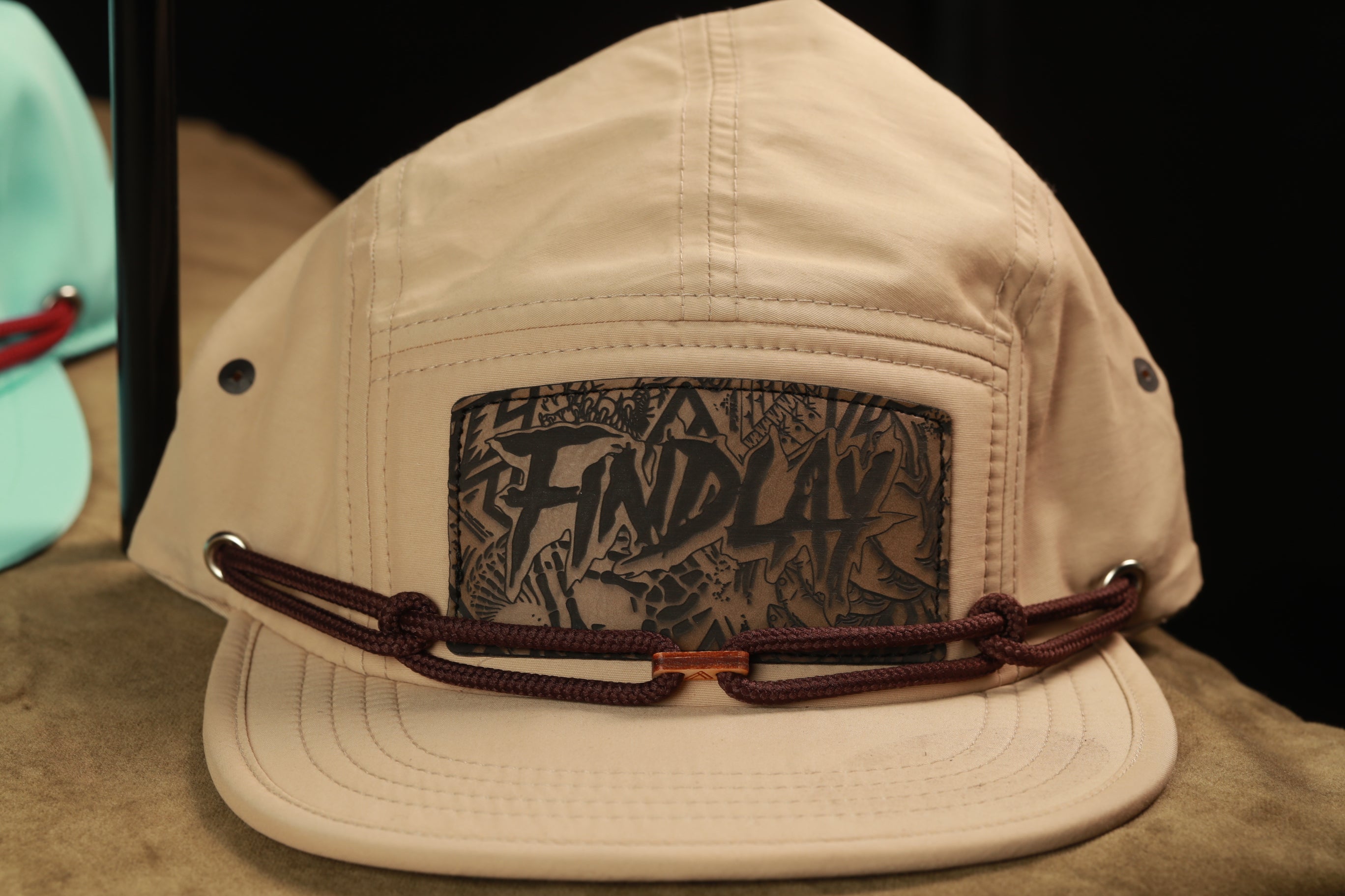 A beige baseball cap with a black graphic design on the front, featuring the word "FIND" prominently displayed.