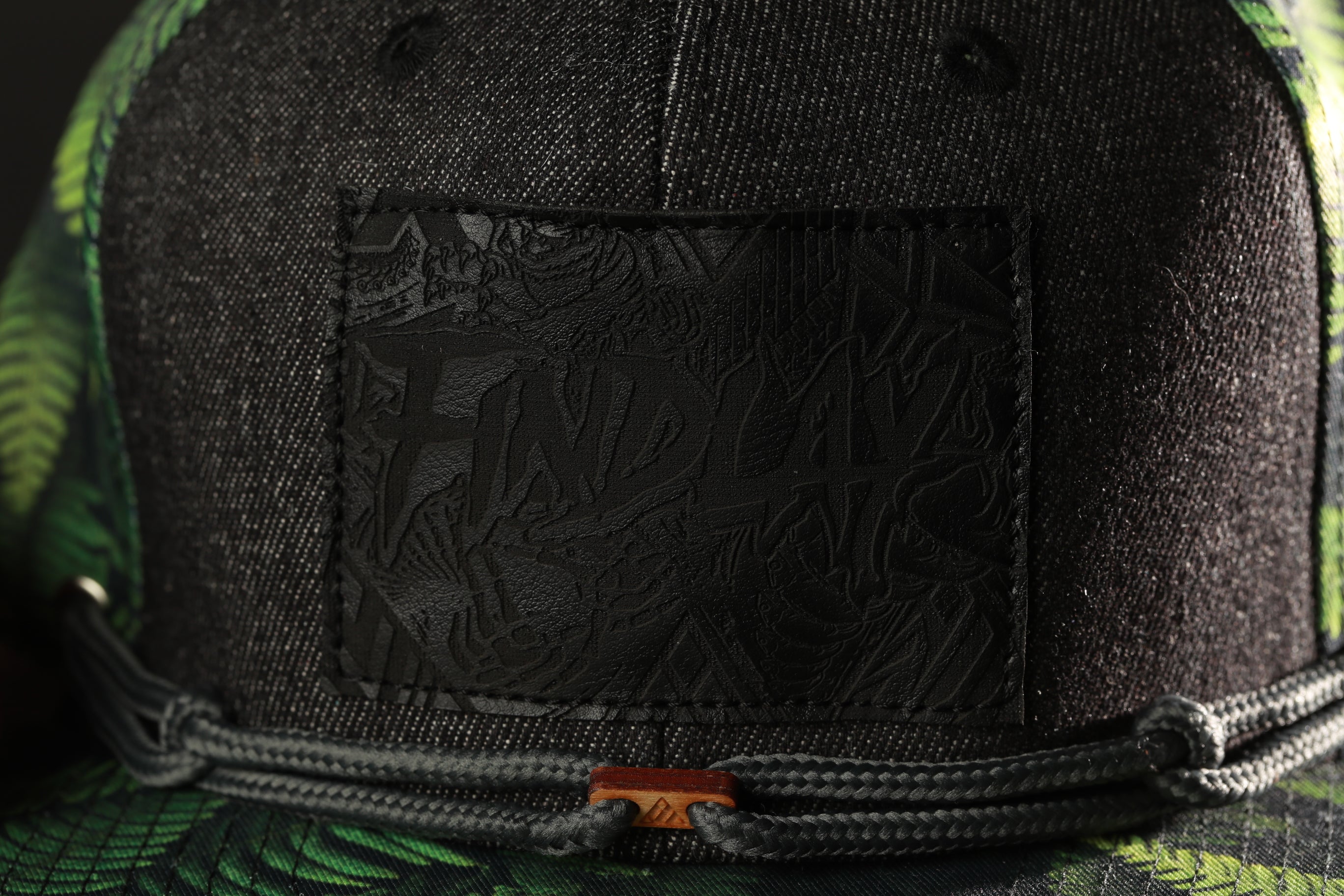 a close-up view of a black baseball cap with a distinctive green and black pattern.
