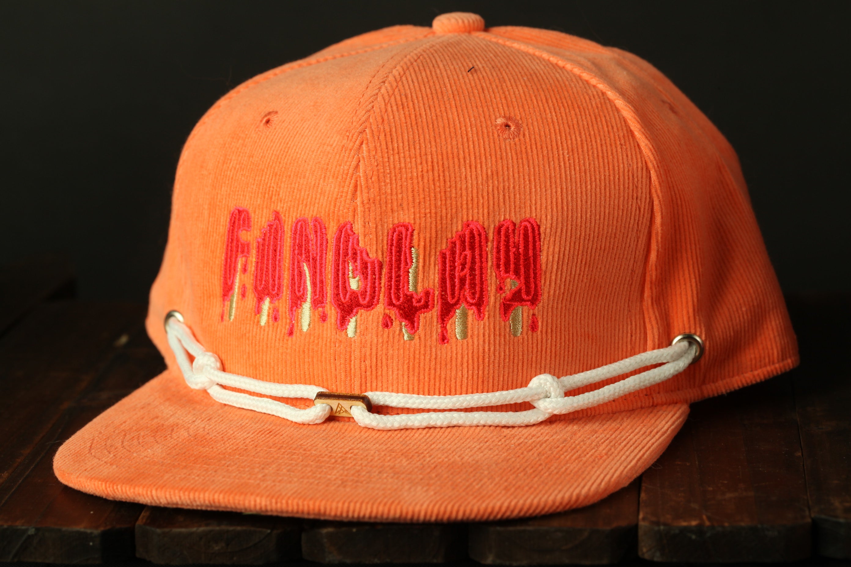 An orange baseball cap with the word "Fang" written on it in red text.