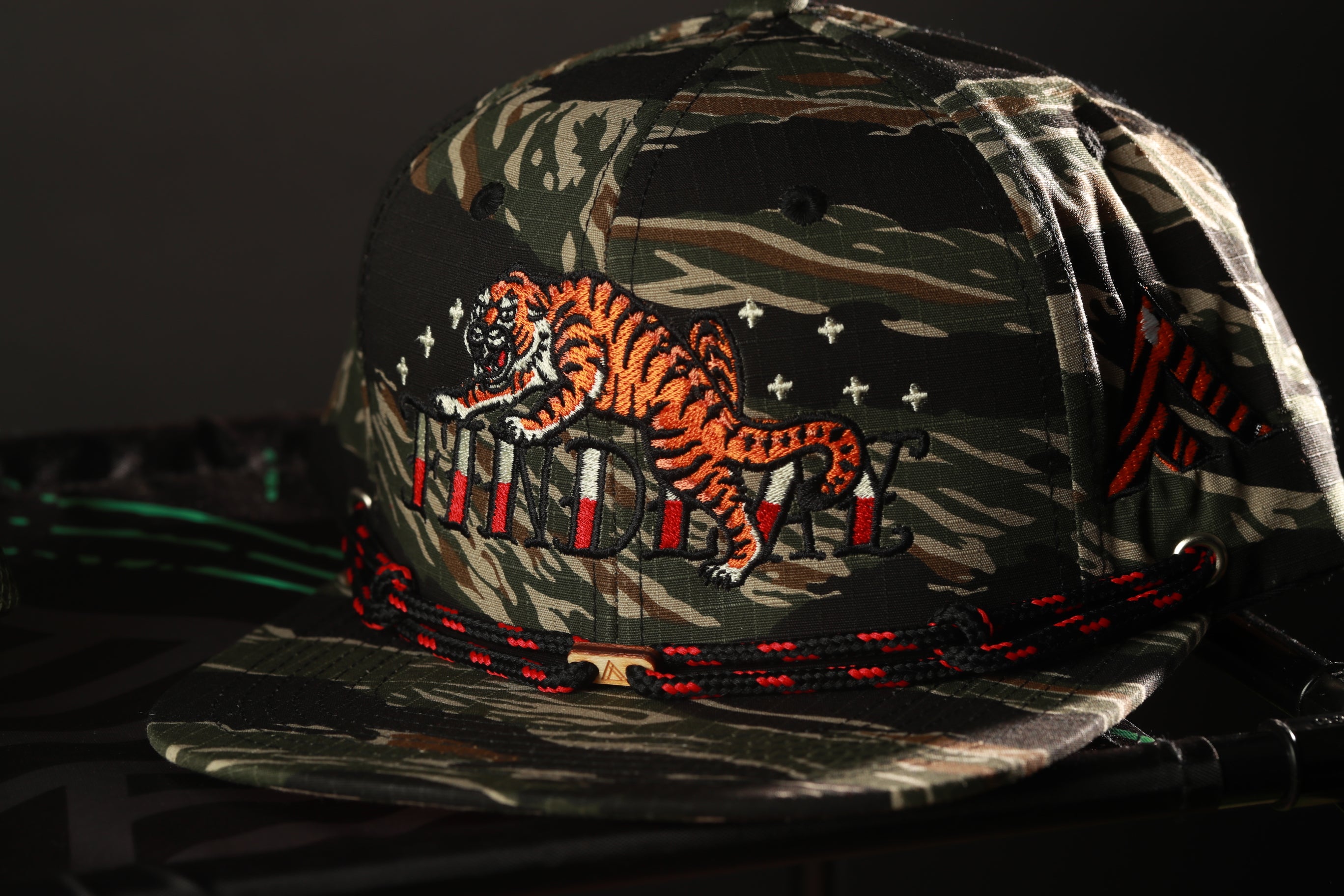 A camouflage baseball cap with a tiger design and the word "Wildlife" printed on it.