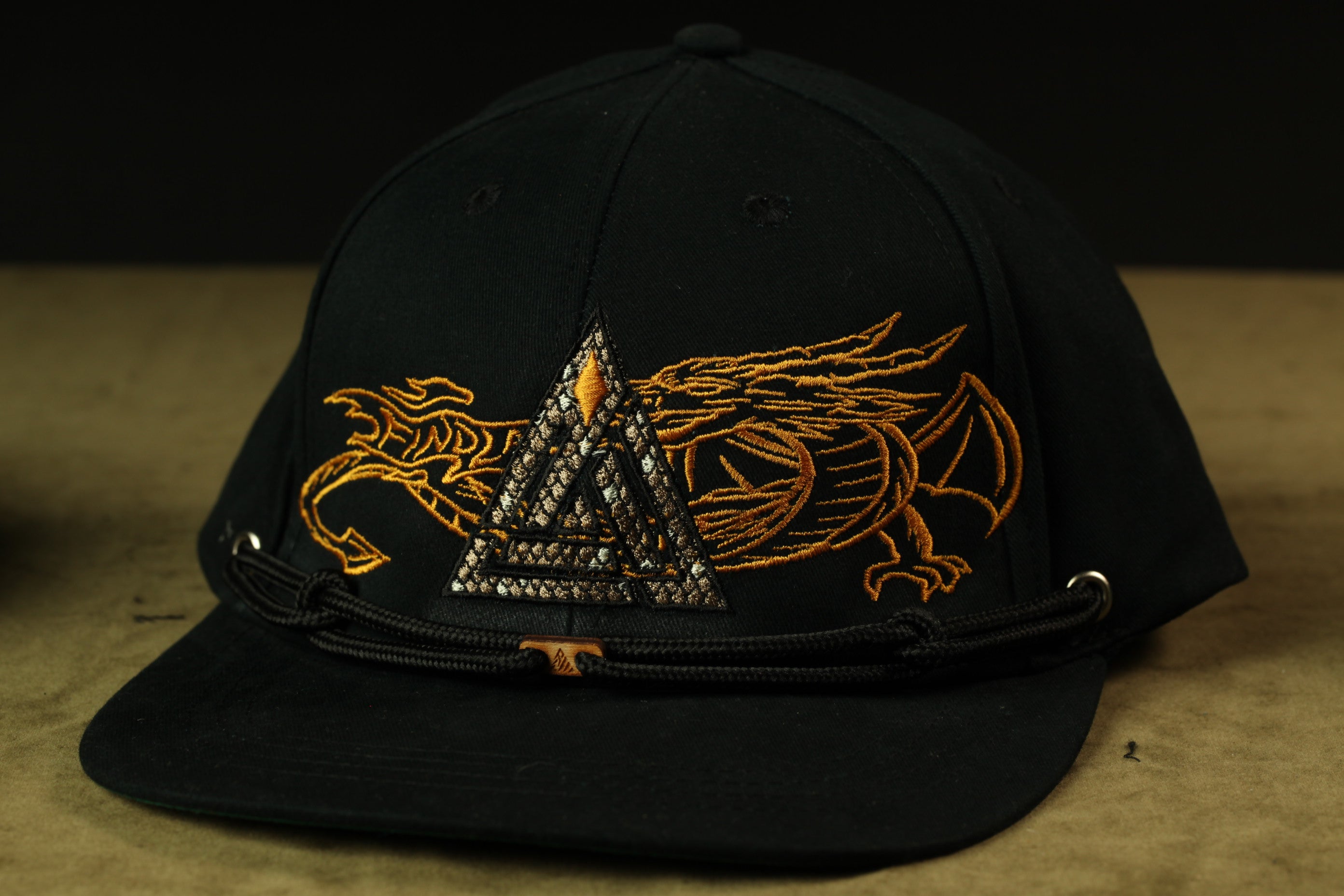 A black baseball cap with a gold dragon design on the front.