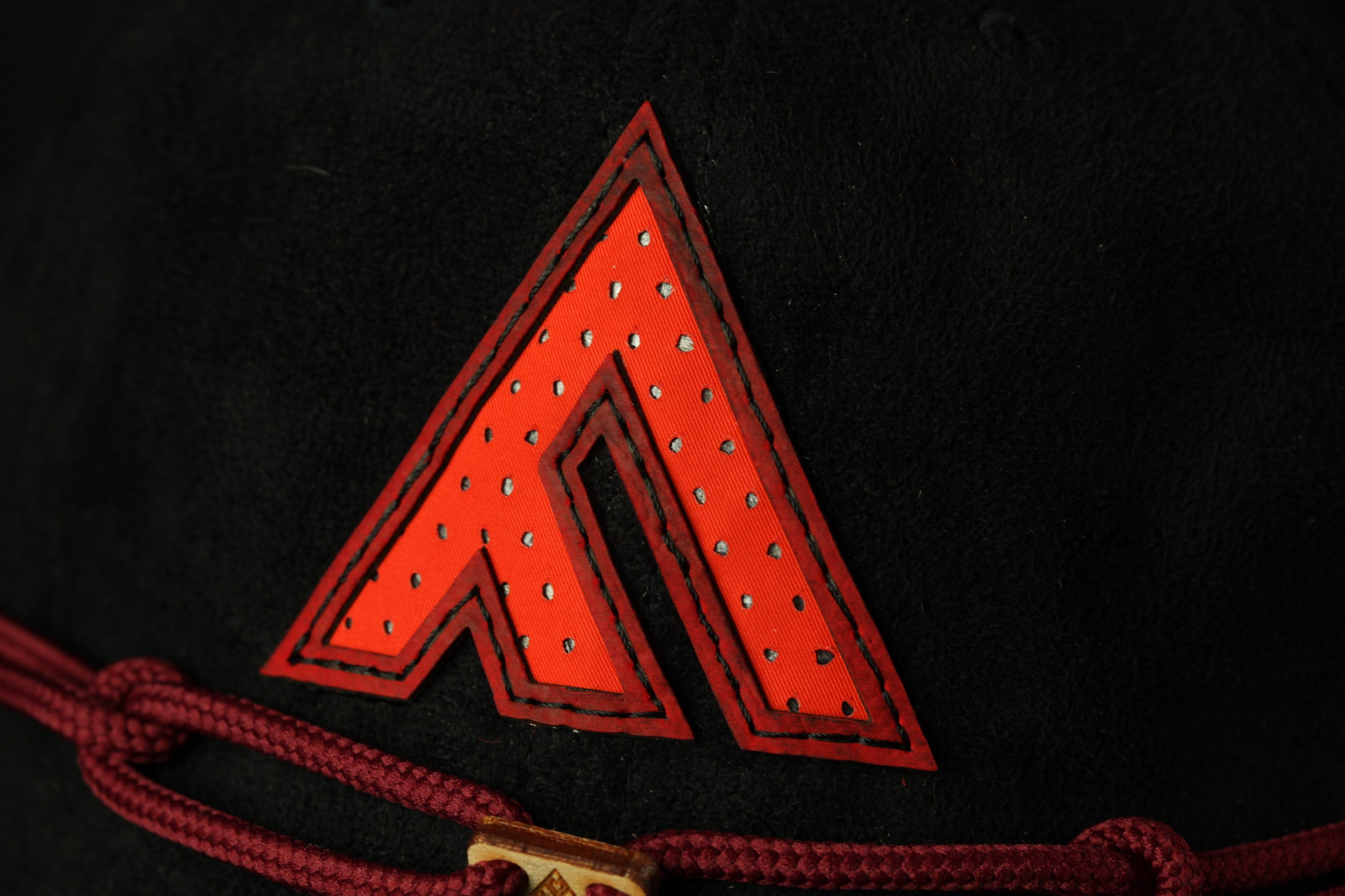 A close-up view of a red, diamond-shaped logo on a black background.
