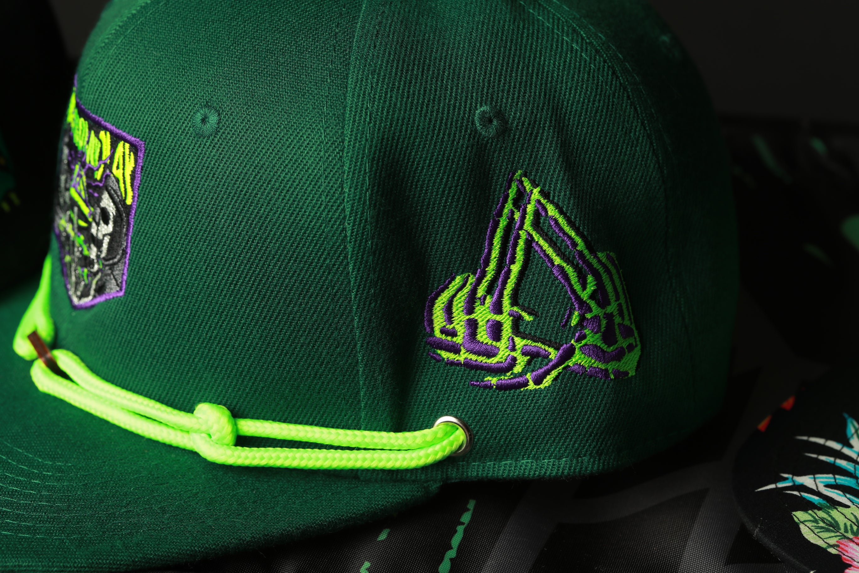 A close-up view of a green baseball cap with a unique embroidered design on the side.