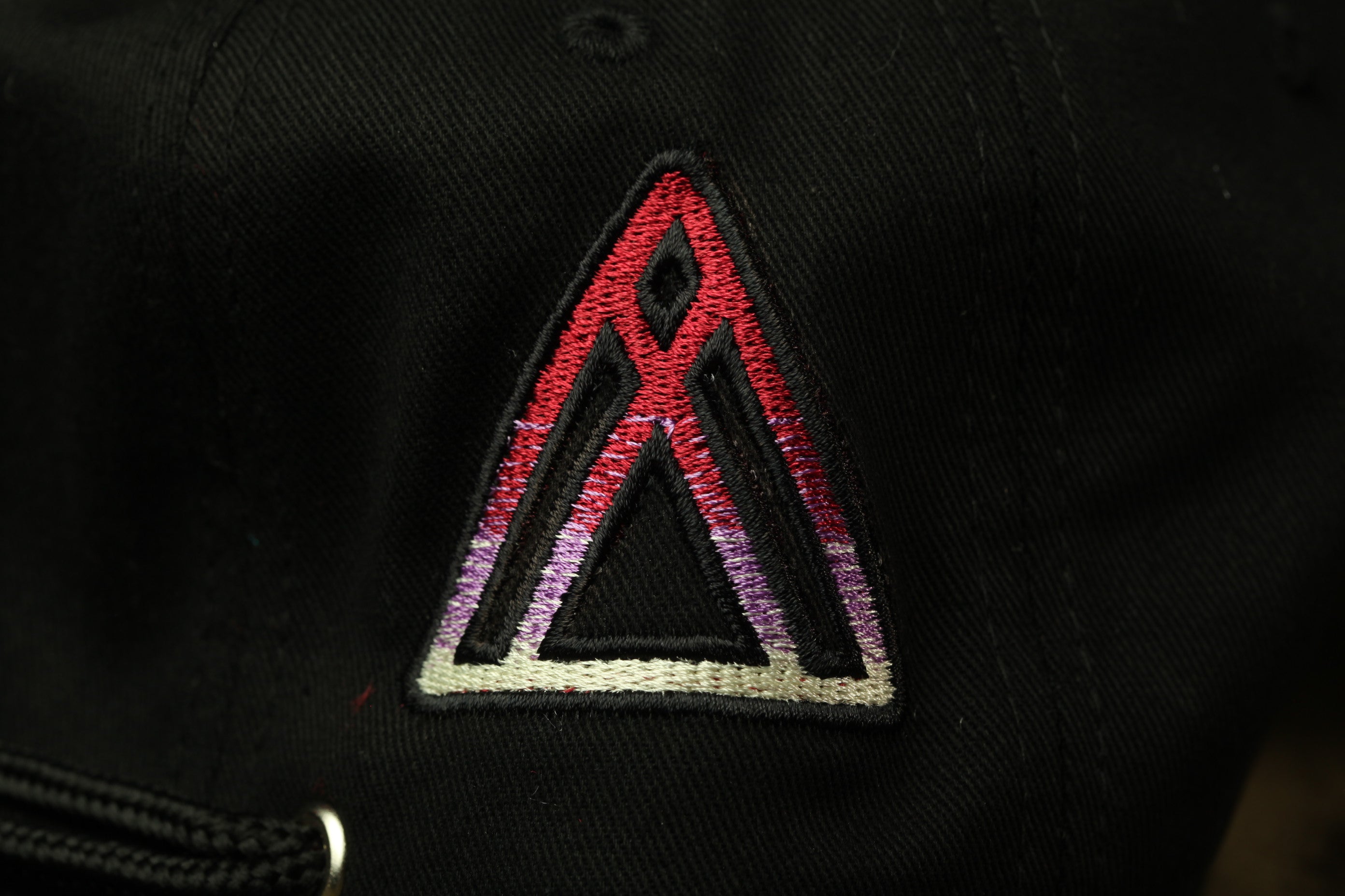 A close-up view of a black fabric with a red and purple geometric pattern, resembling a triangle or a symbol.