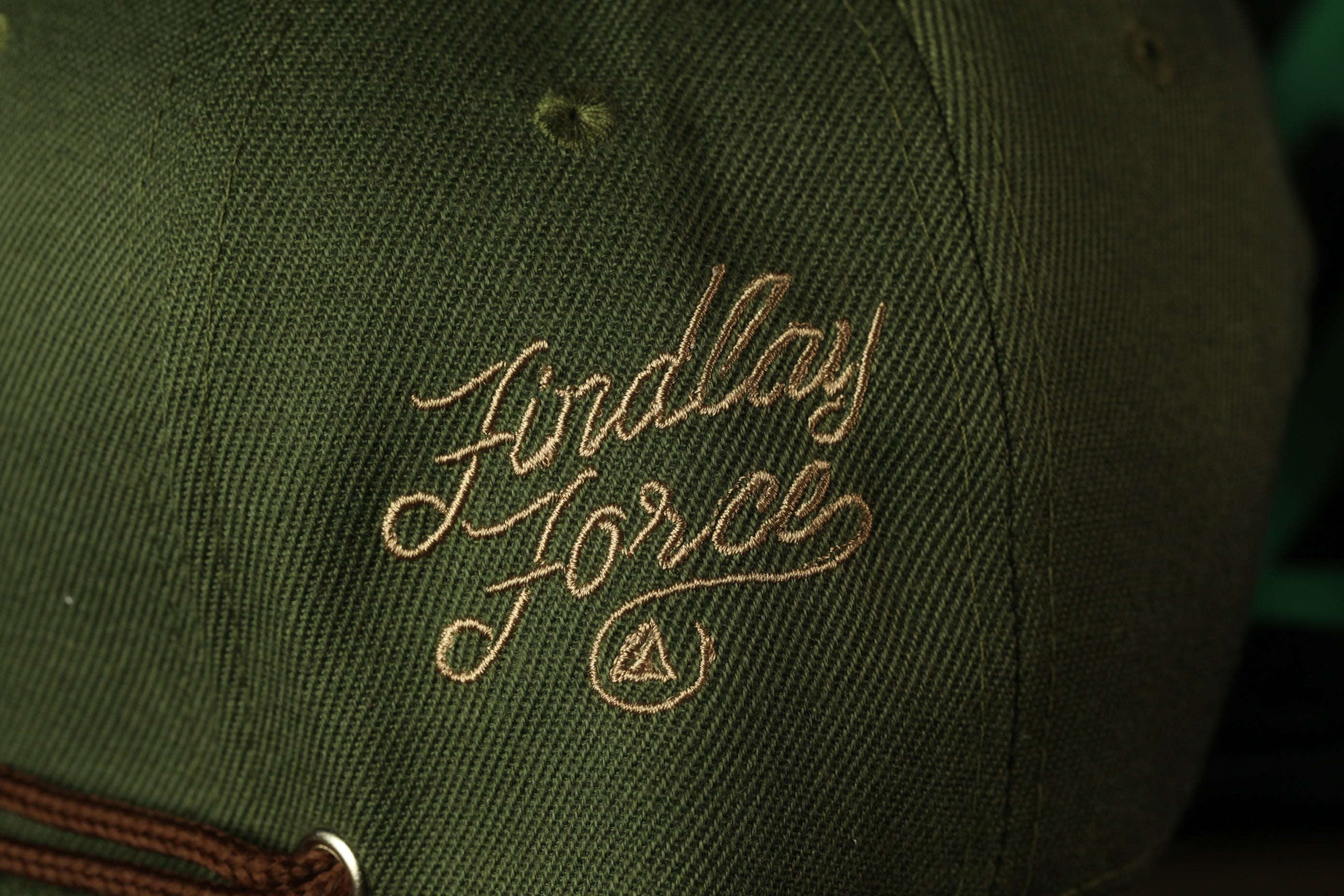 A close-up view of a green baseball cap with the embroidered text "Ford Force" on it.