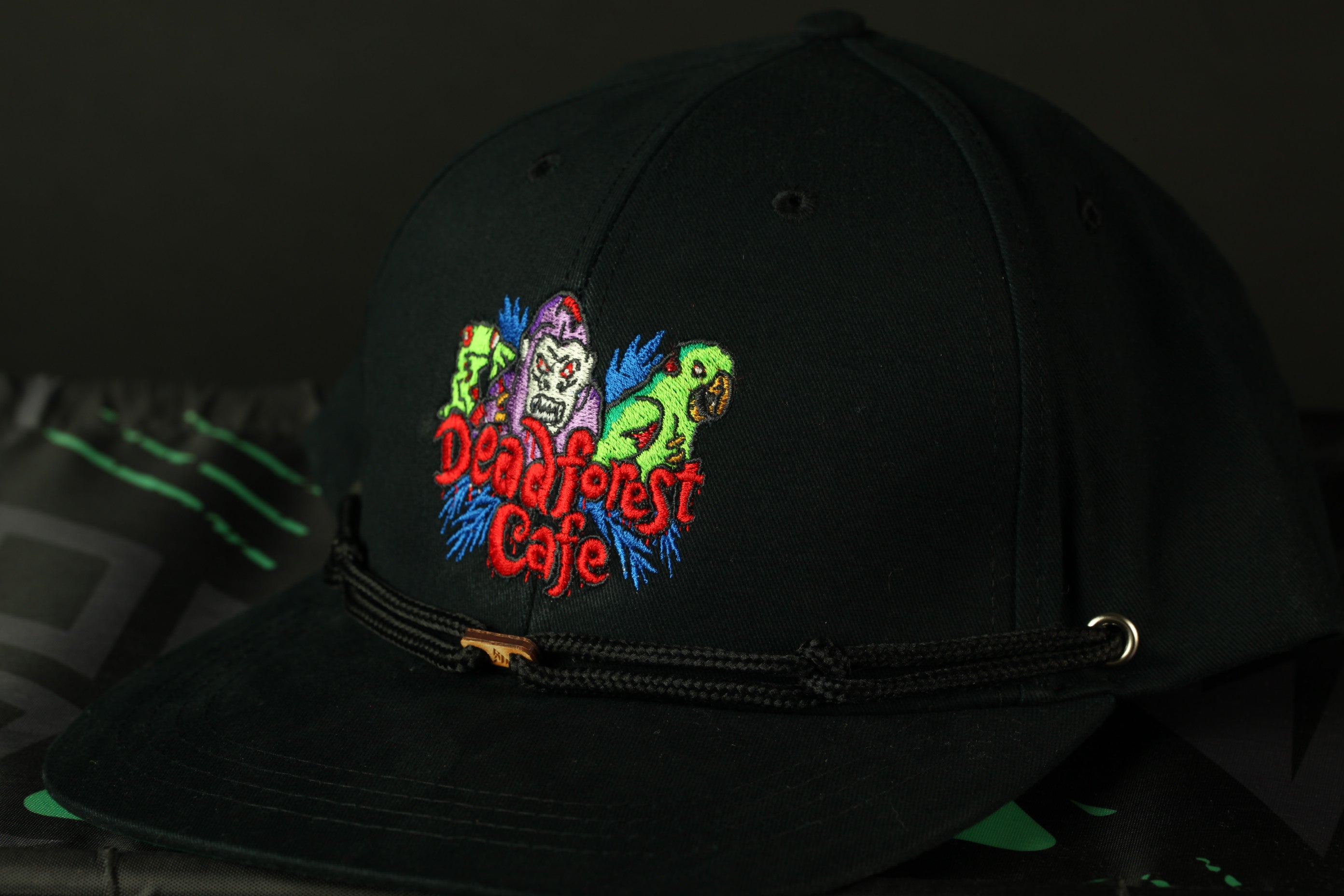 A black baseball cap with a colorful embroidered logo on the front, featuring a group of cartoon-like characters.
