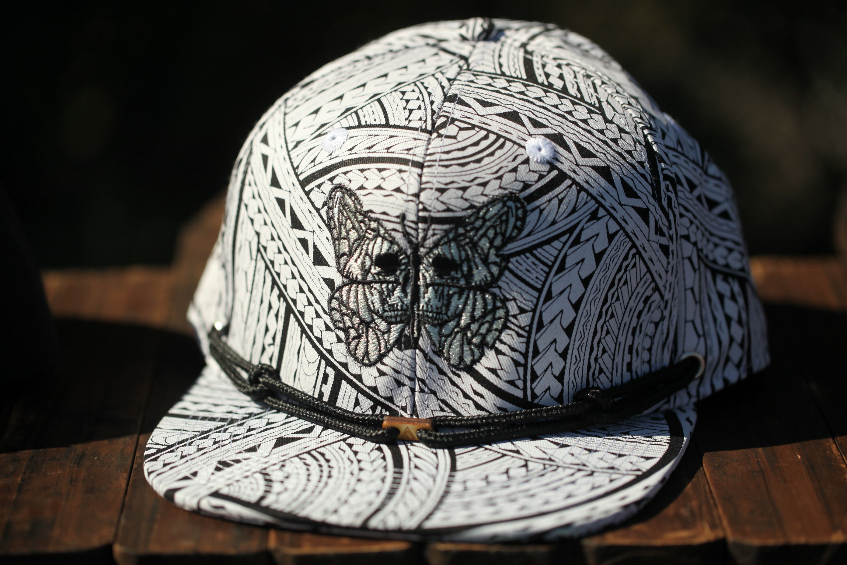 A close-up image of a black and white patterned baseball cap with a butterfly design on the front.