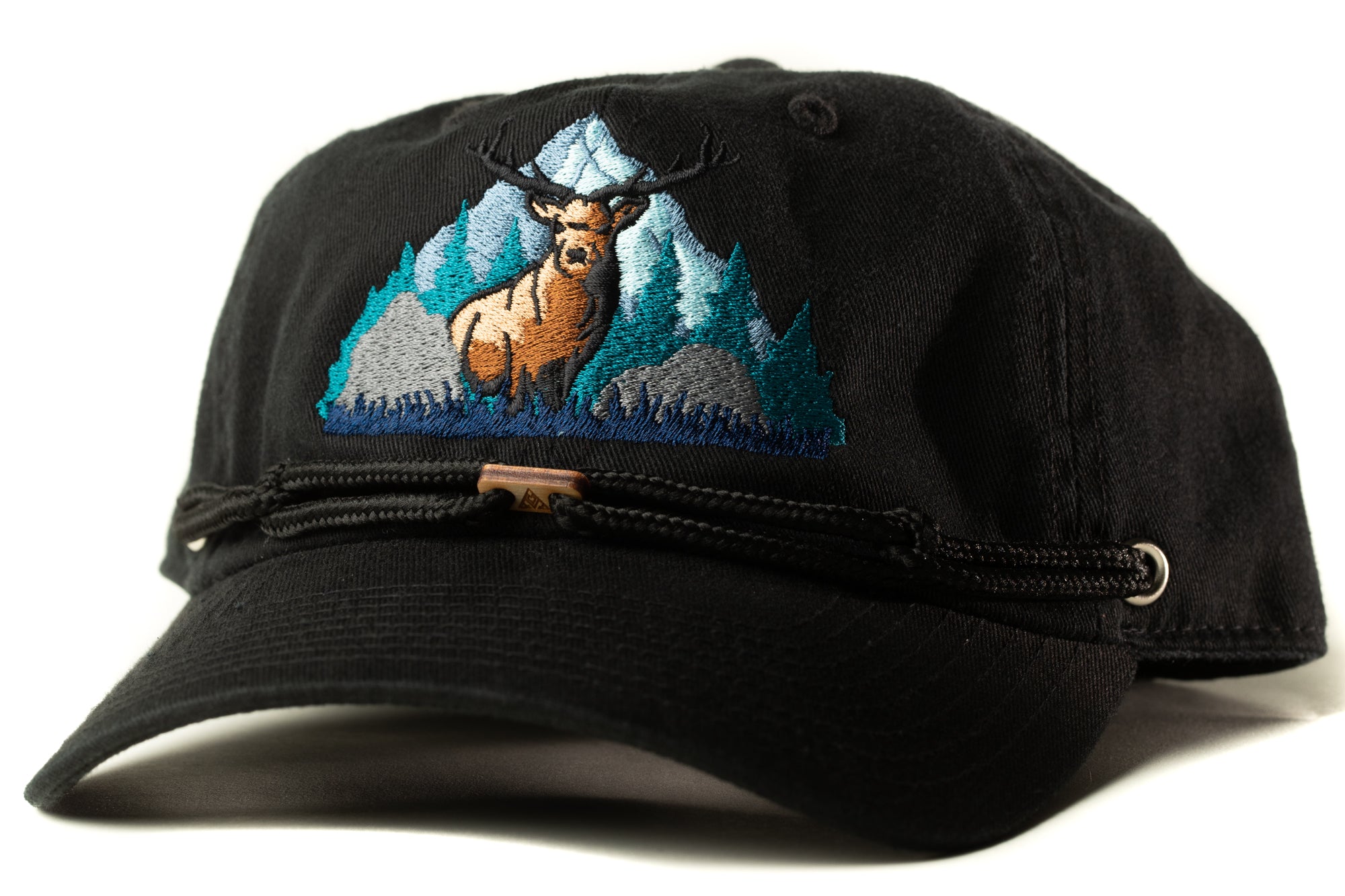 A black baseball cap with a detailed embroidered design depicting a deer standing in a mountainous landscape.